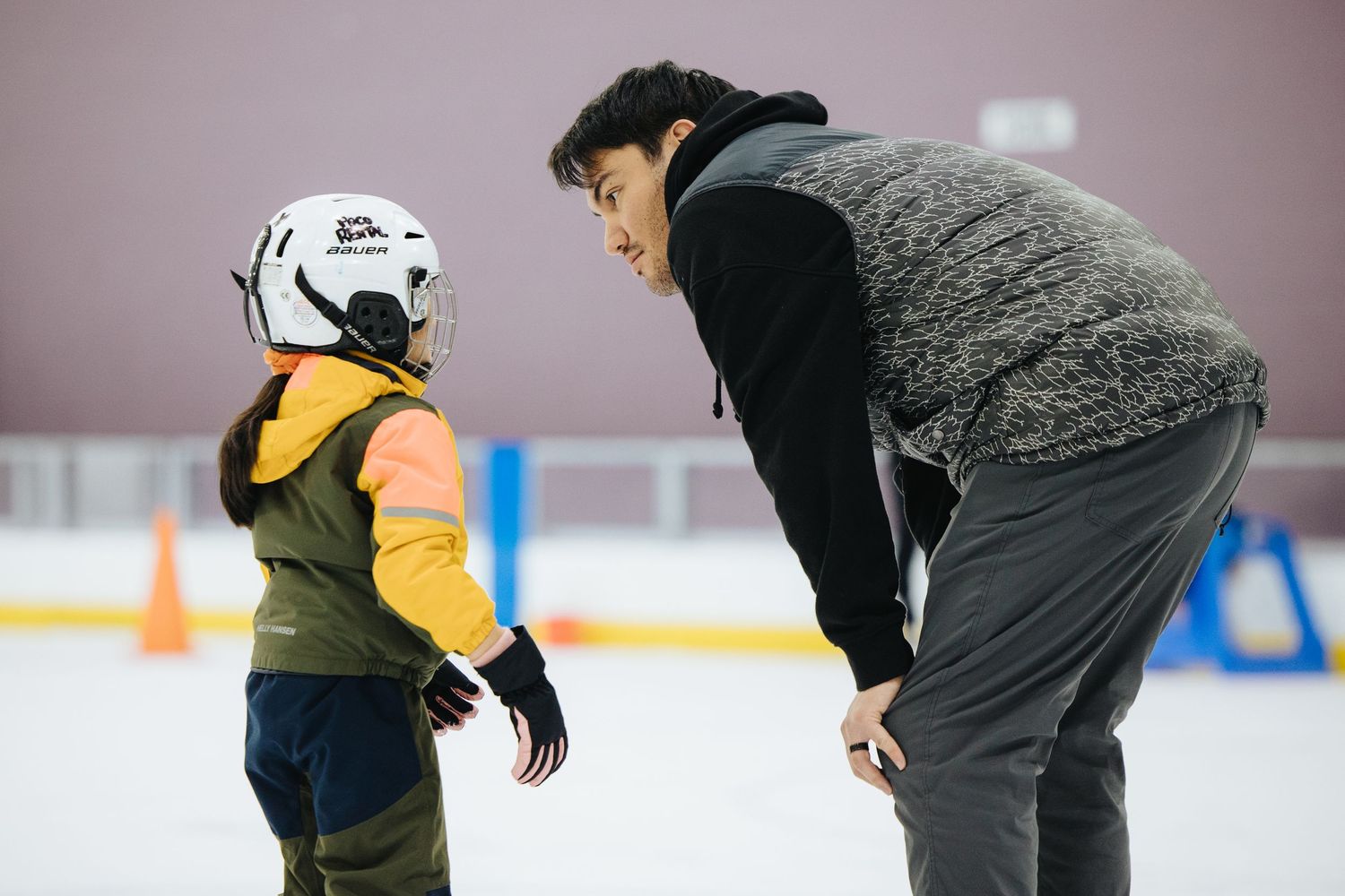 People practicing ice skating skills in a recreational rink setting.