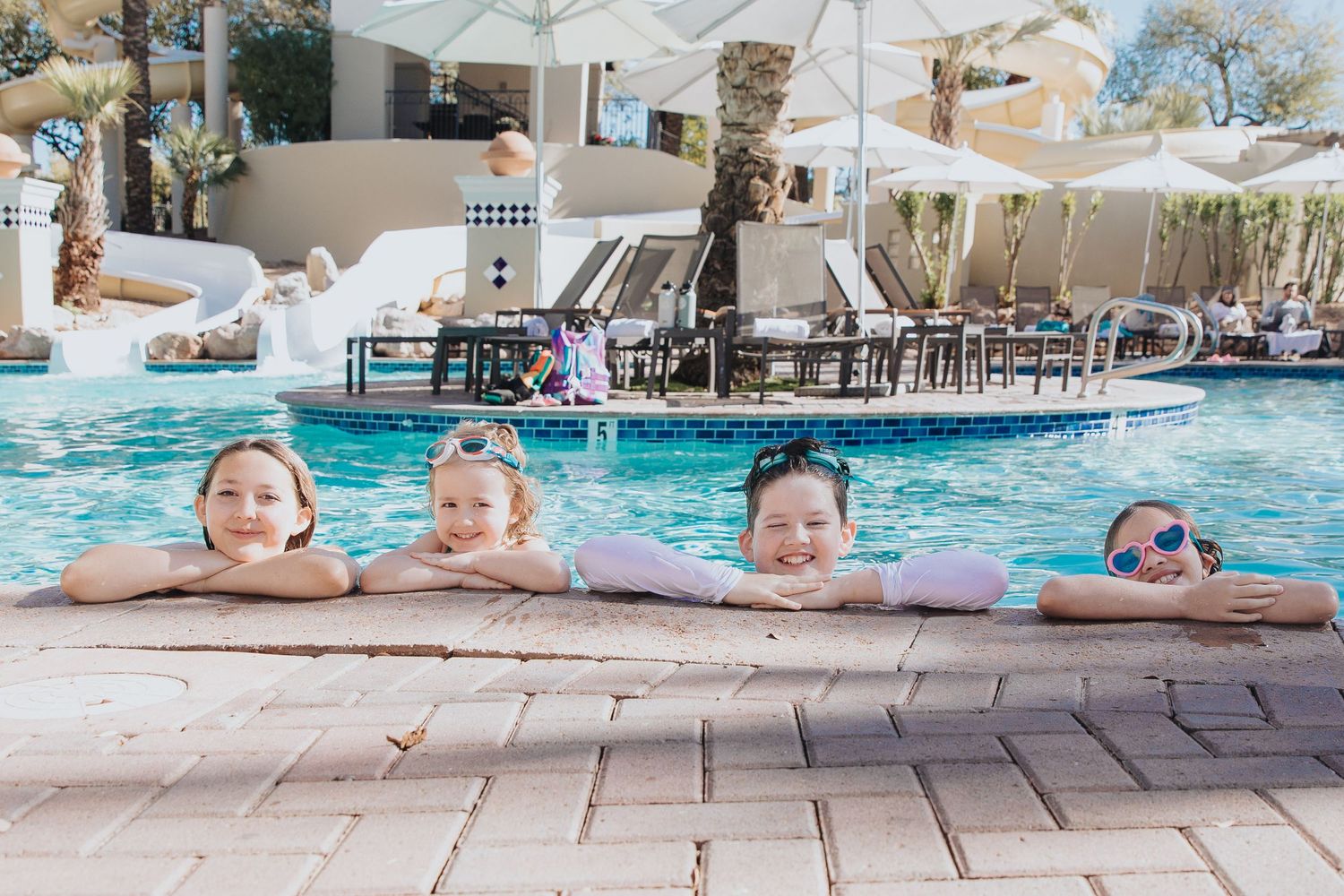 Resort swimming pool scene with white umbrellas and loungers along the deck.