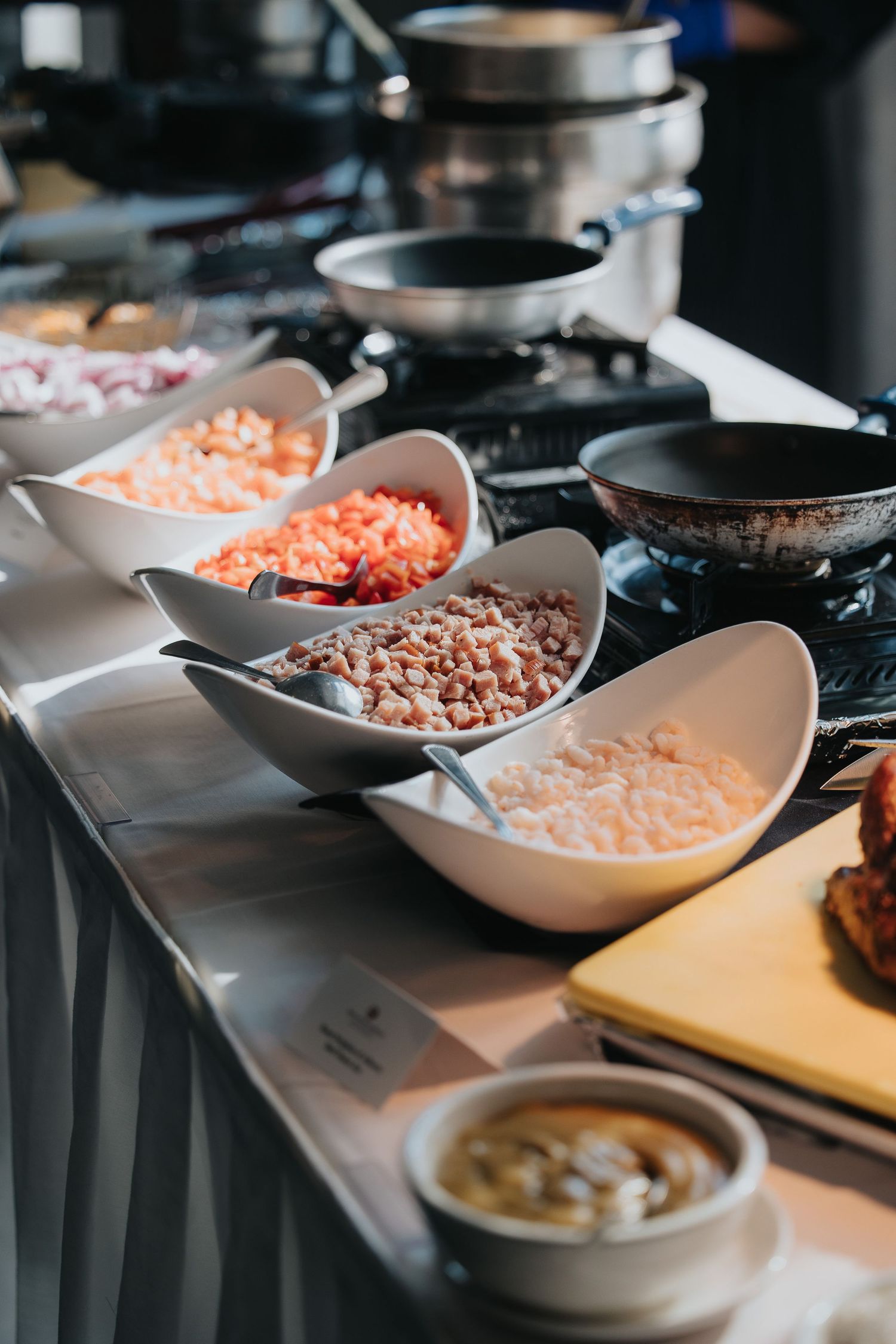 Various ingredients and toppings displayed in white serving bowls on a dark surface for meal preparation.