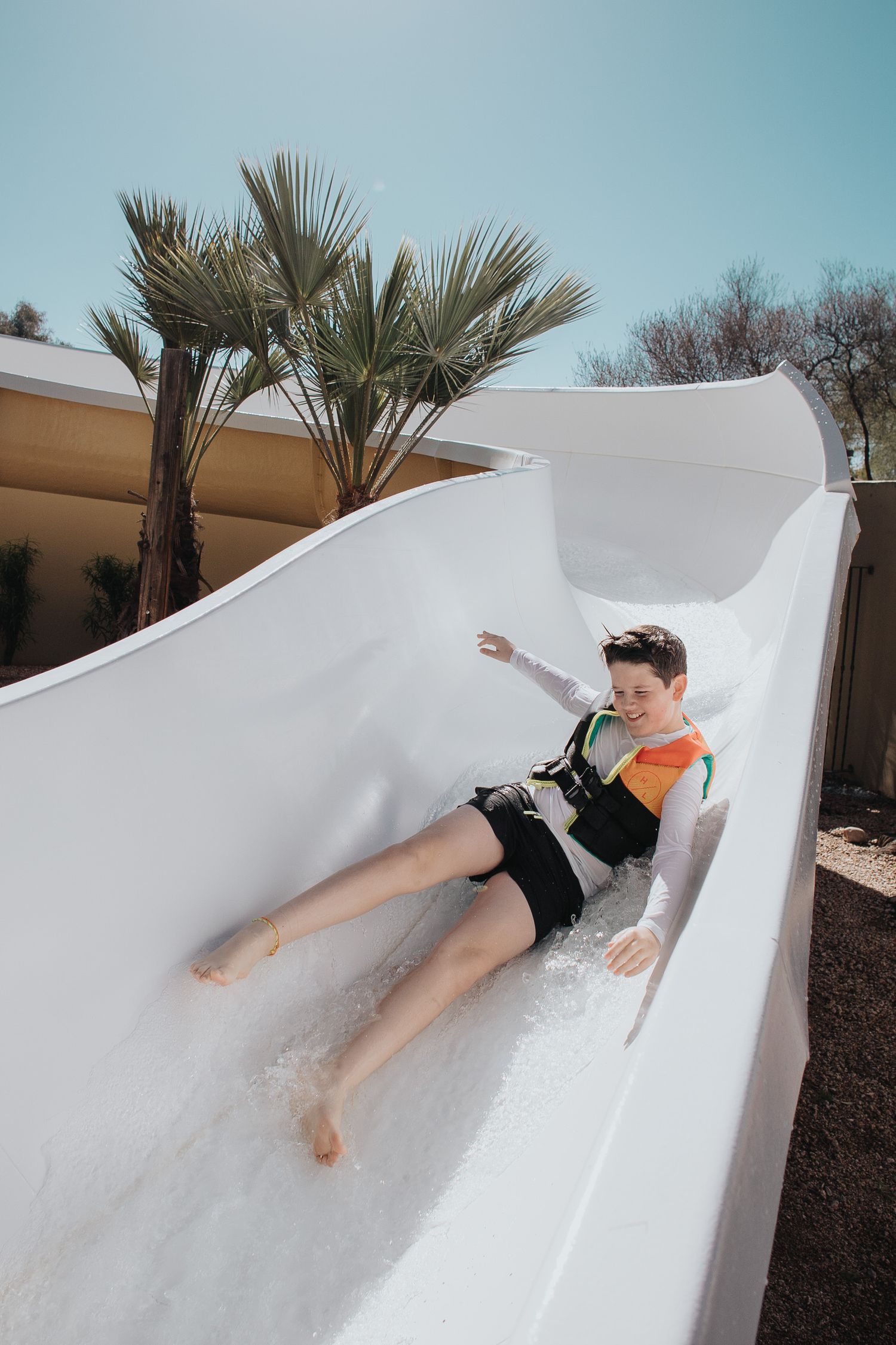 Person sliding down a white water slide at an outdoor water park.