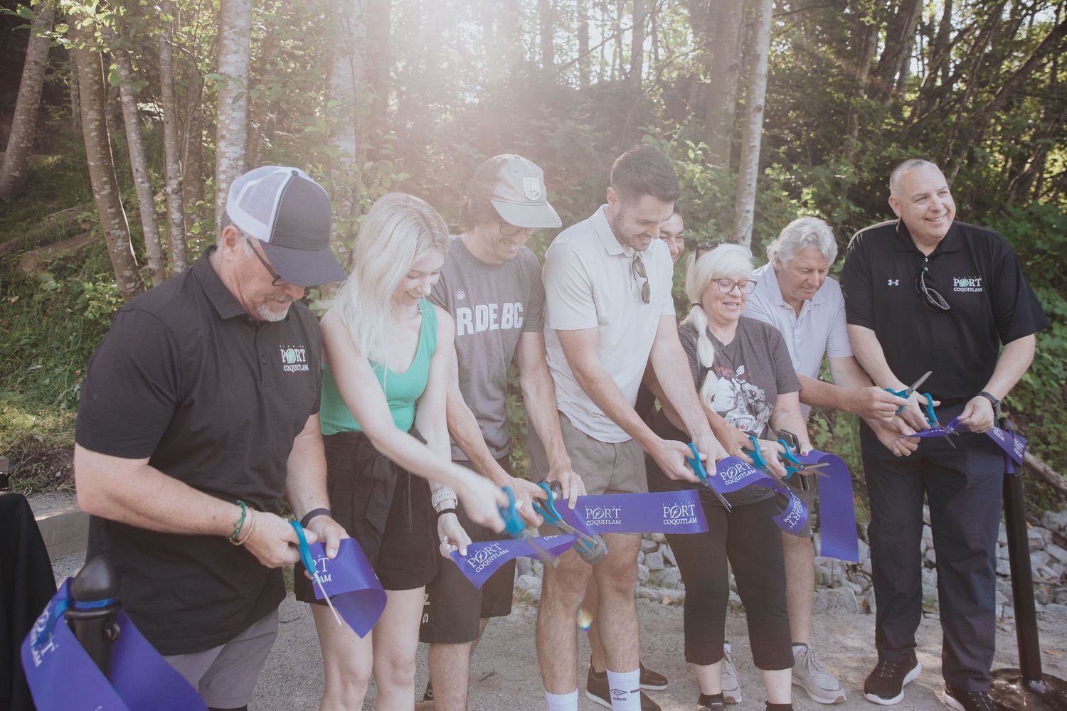 People gathered in a wooded area holding blue bottles during an outdoor event.