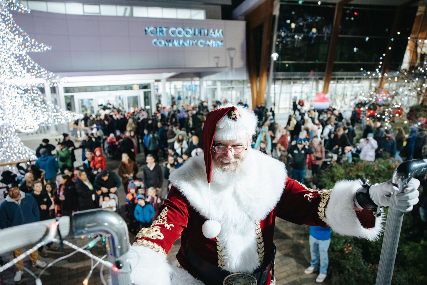 Large crowd gathered in festive indoor venue with holiday decorations.