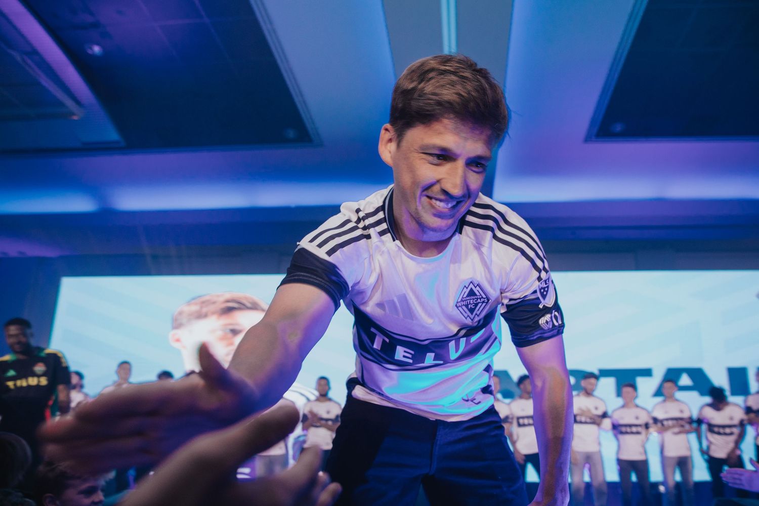 Professional gamers celebrating victory at an esports tournament with blue stage lighting.