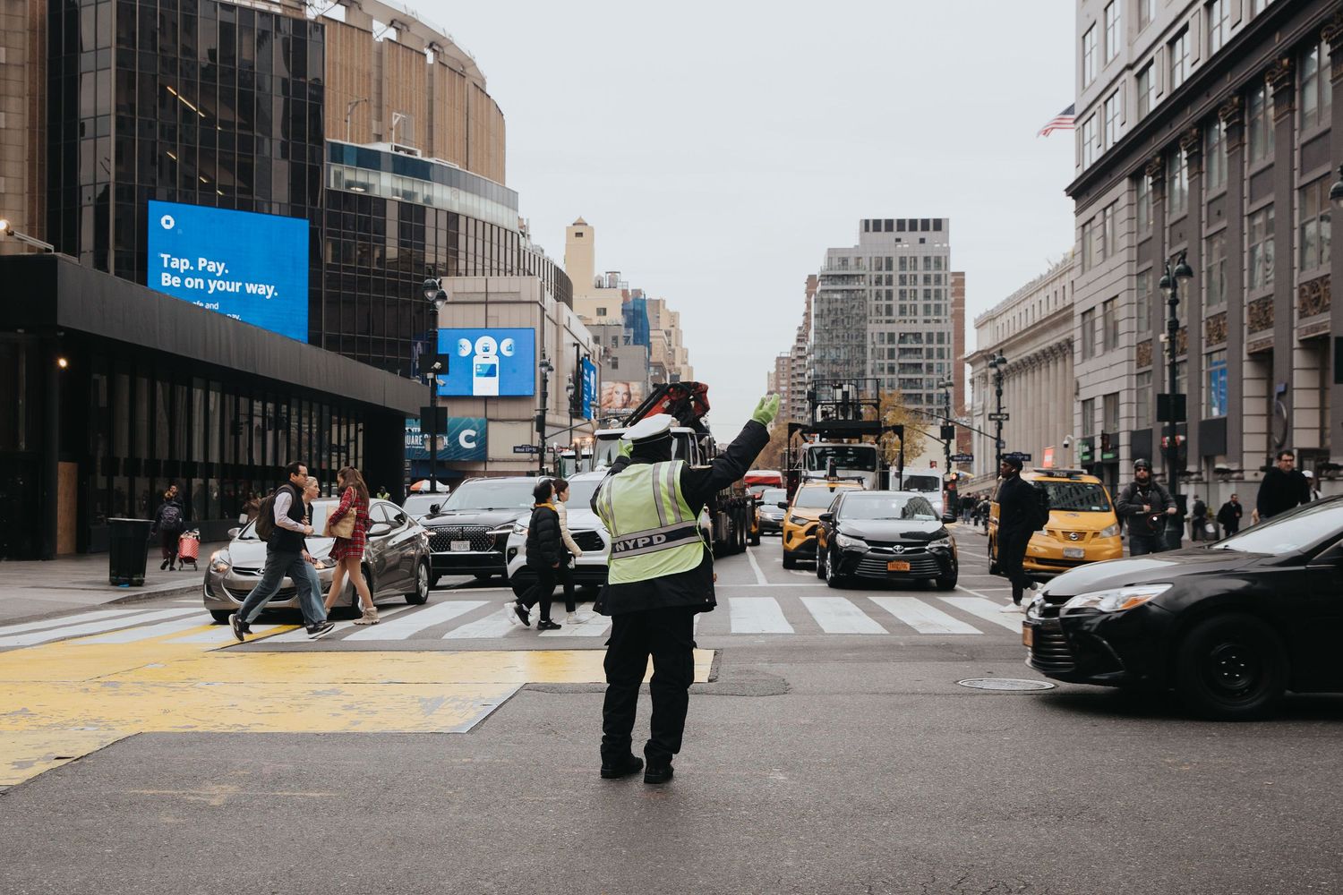 Urban street scene with pedestrians and buildings in muted tones.
