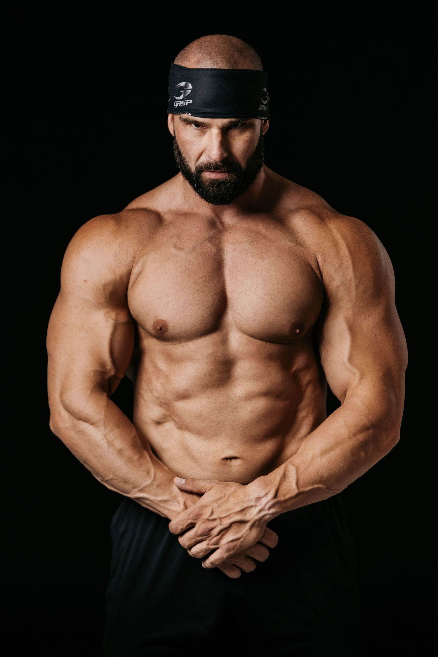 Dramatic studio photograph of muscular physique against black background.