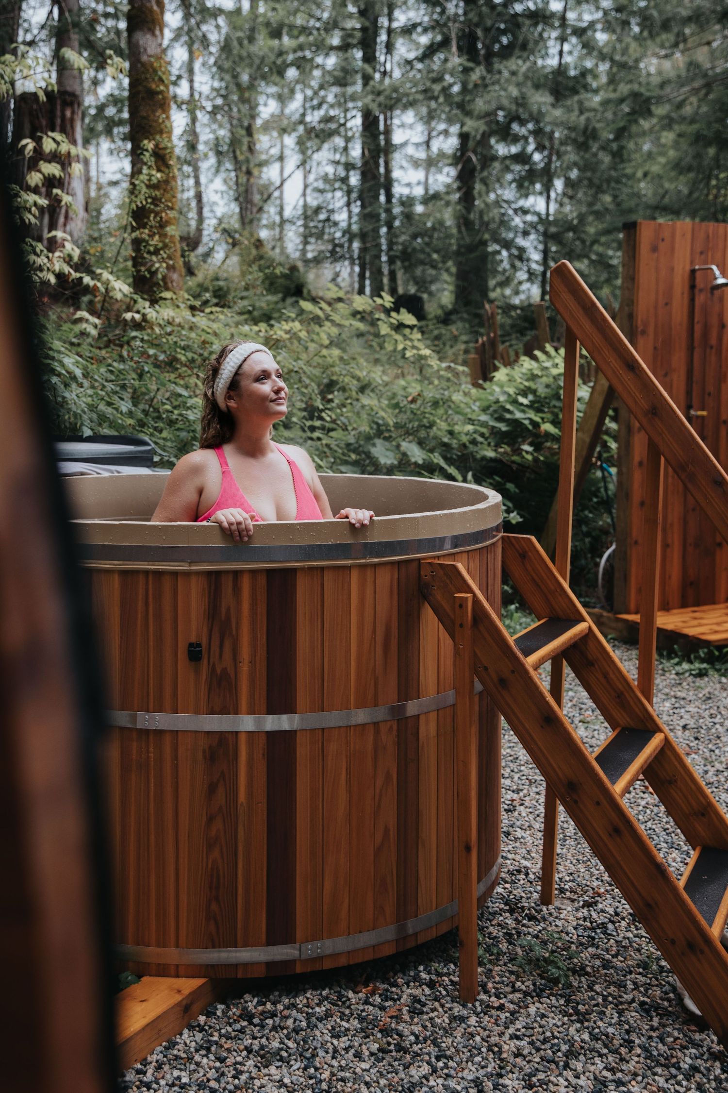 Wooden hot tub nestled among trees in a peaceful forest setting.