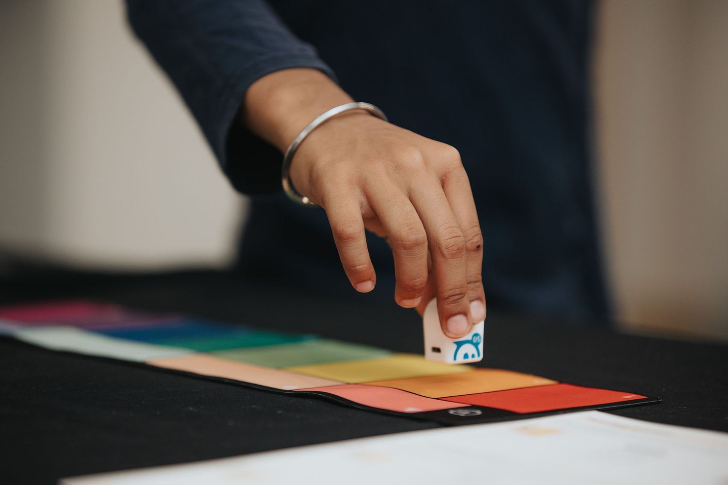 Close-up shot of hands working with colorful materials on a table surface.