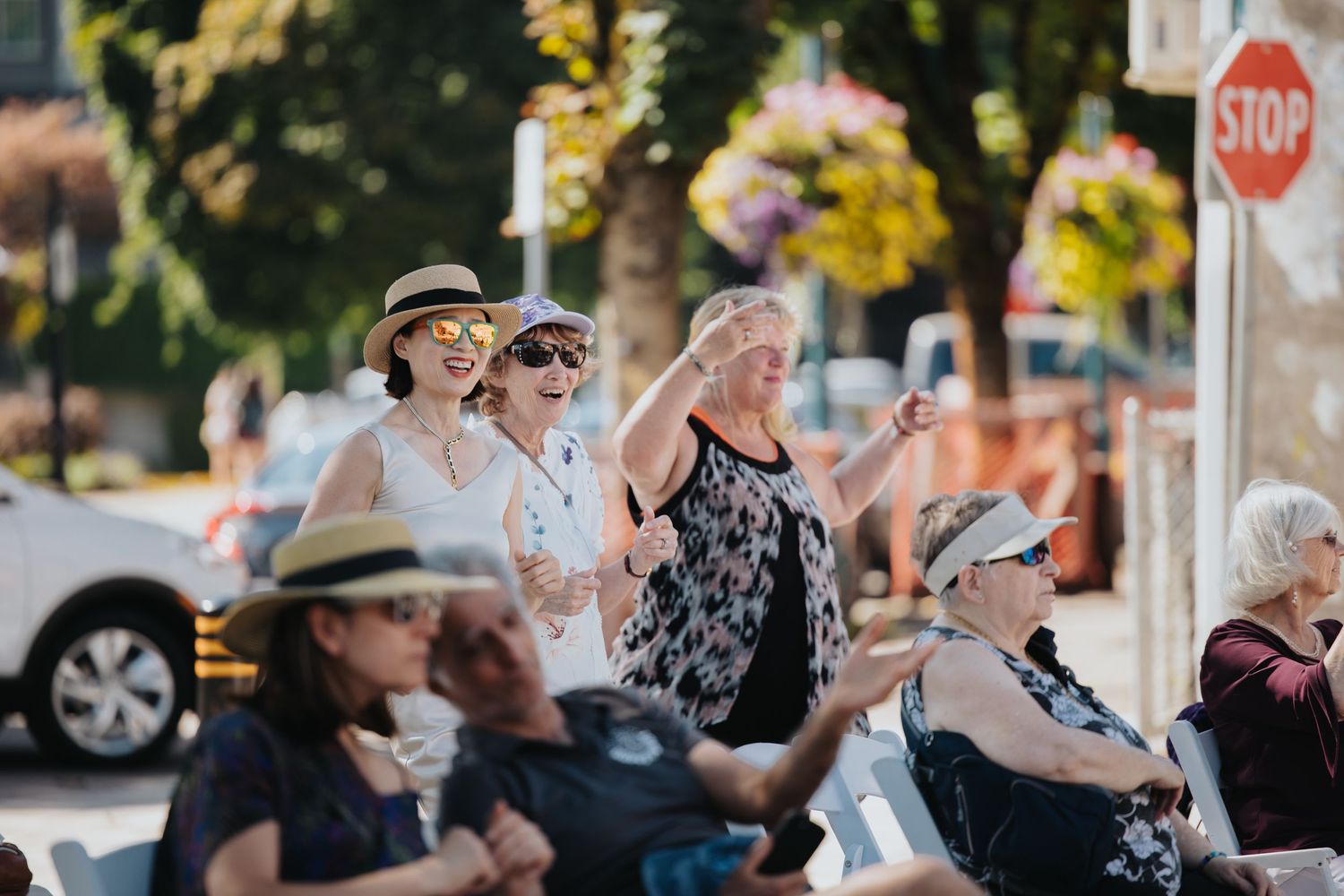 Audience members watching an outdoor performance while seated in chairs.