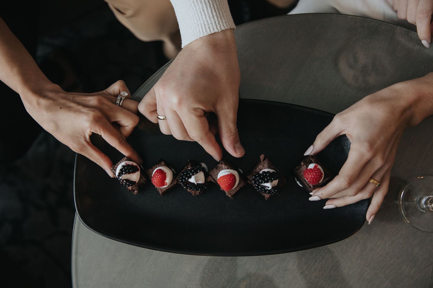 Hands arranging small decorative items on a black surface.