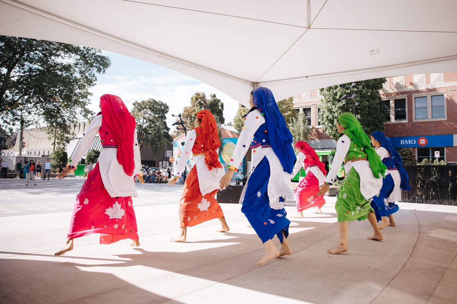 Colorful performance with dancers in flowing robes moving across outdoor stage.