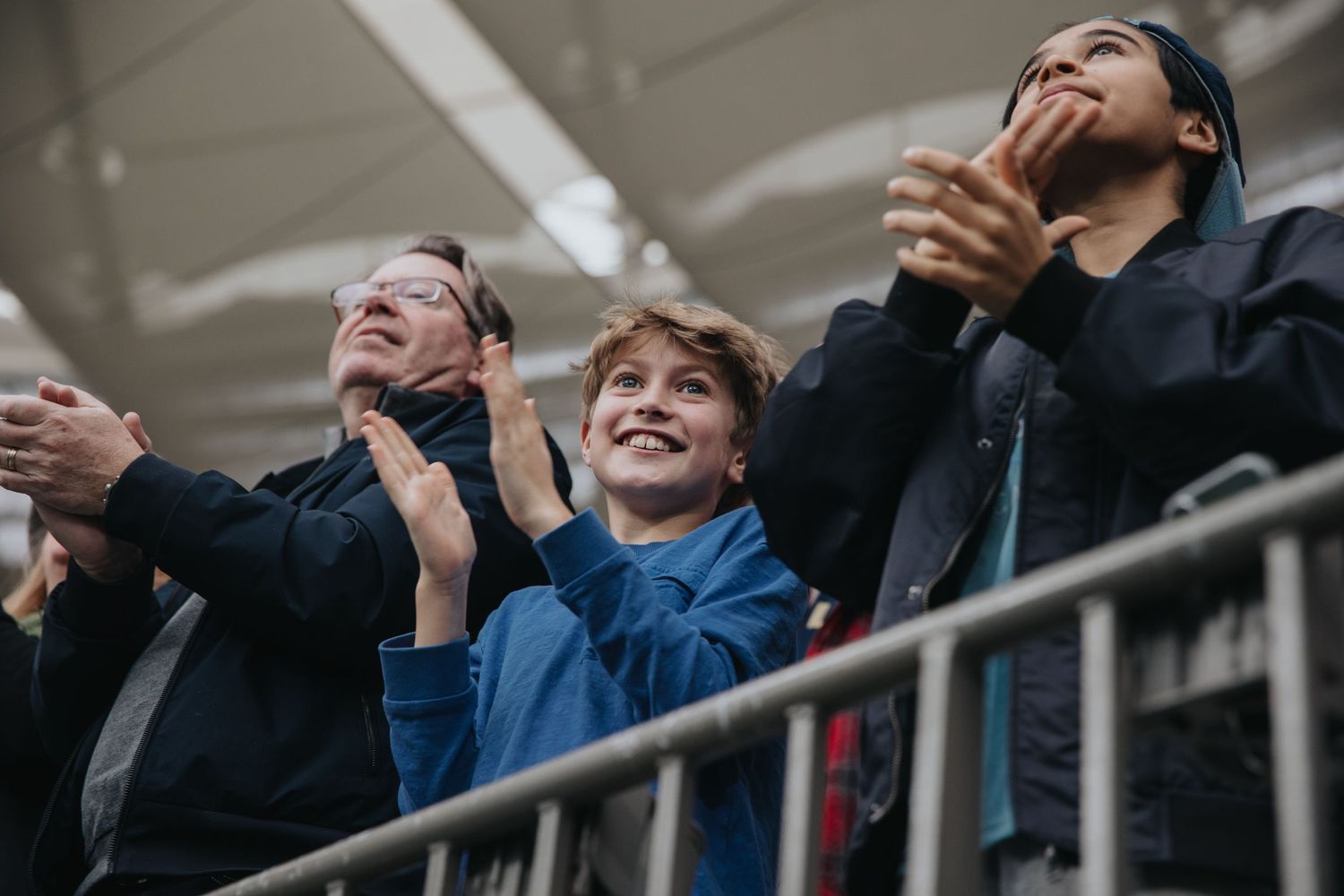 Excited sports fans cheering from stadium seats during live match.
