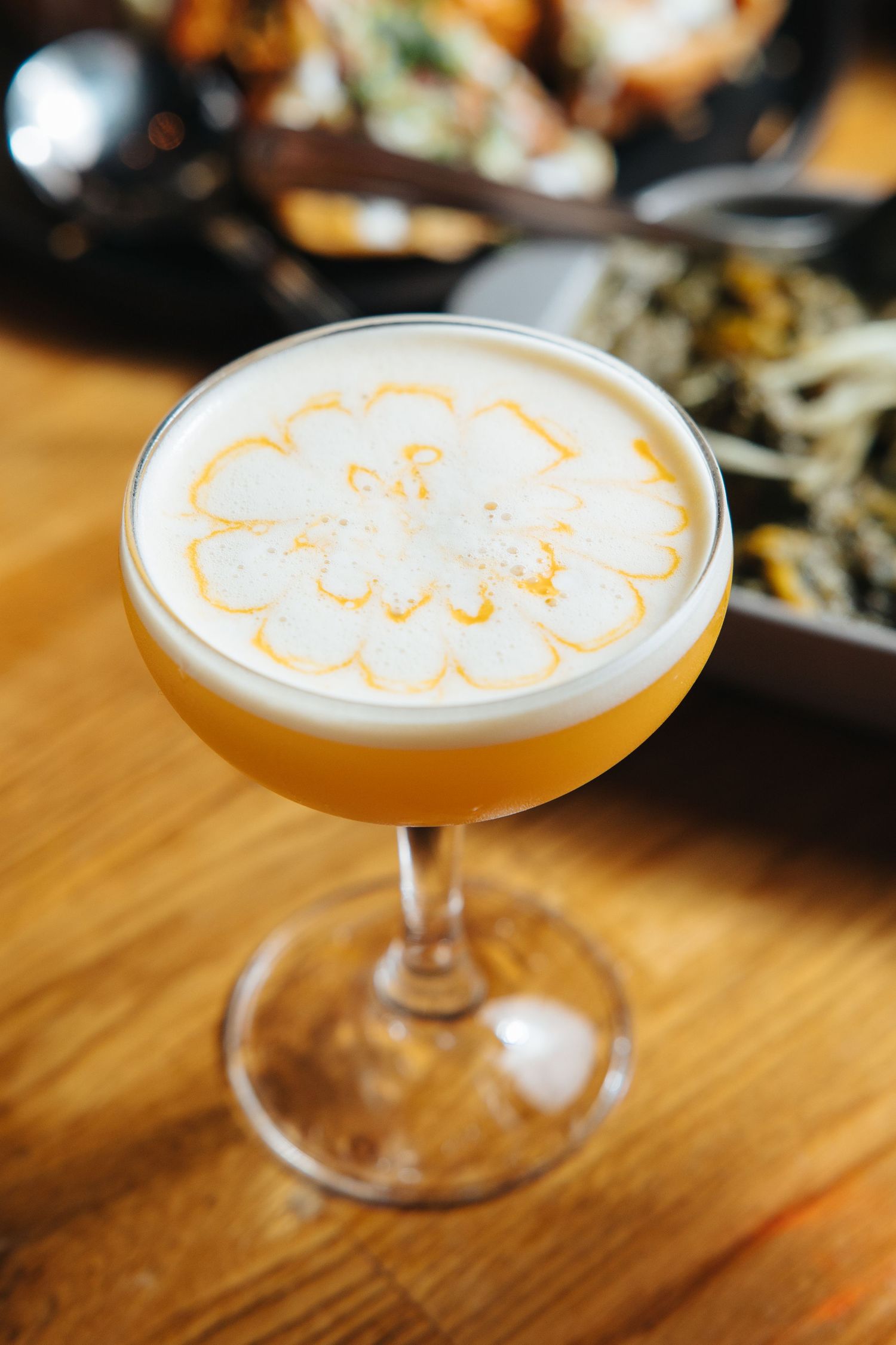 Elegant cocktail glass with frothy top and decorative foam art pattern.