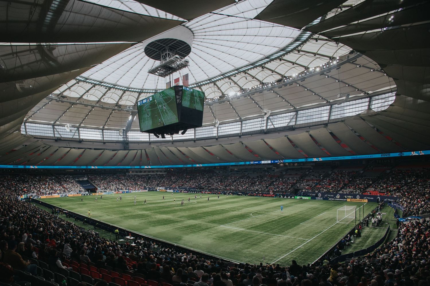 Interior view of a large stadium with retractable roof and bright lighting.