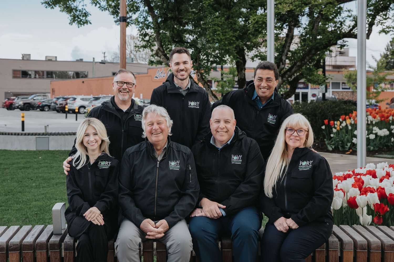 Group portrait of staff members in coordinated black uniforms outside a building.