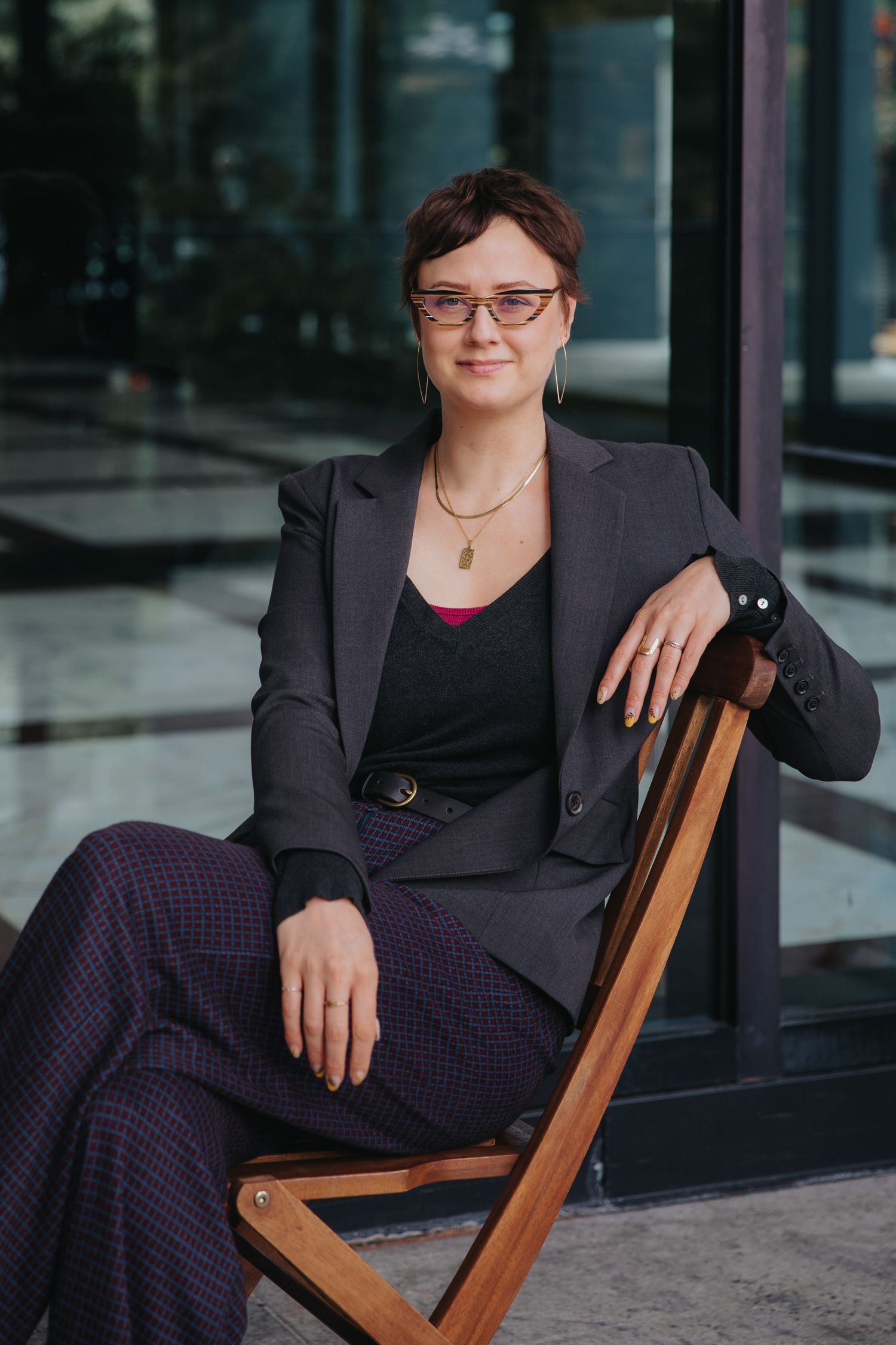 Professional portrait of someone seated in a wooden chair wearing a dark business suit.