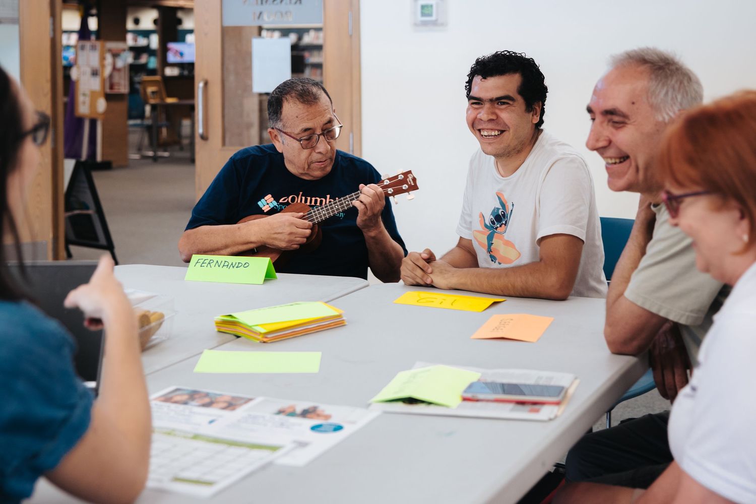 Group of people participating in a discussion around a table with colorful papers.