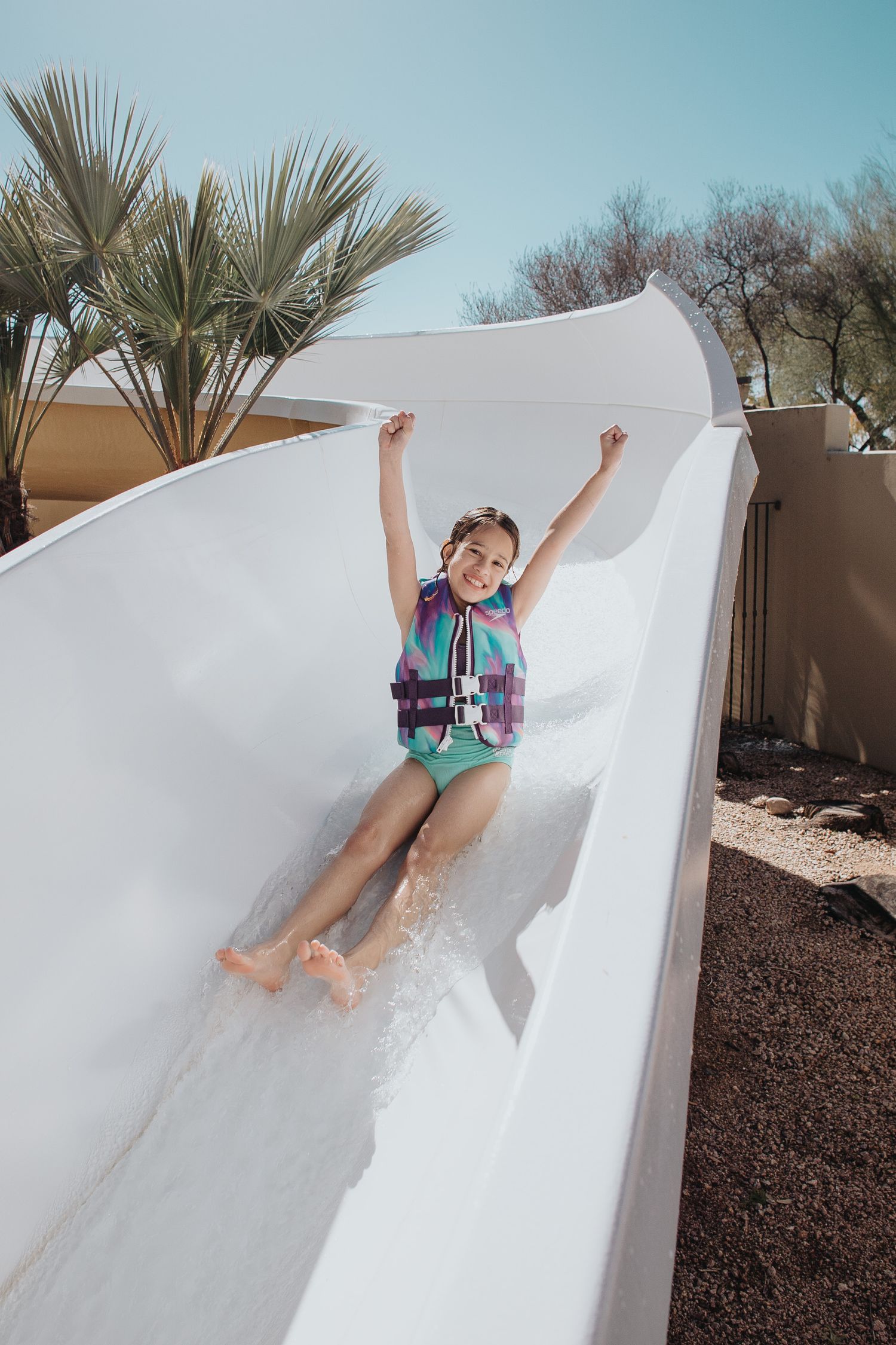 Someone having fun going down a curvy white water slide with arms raised.