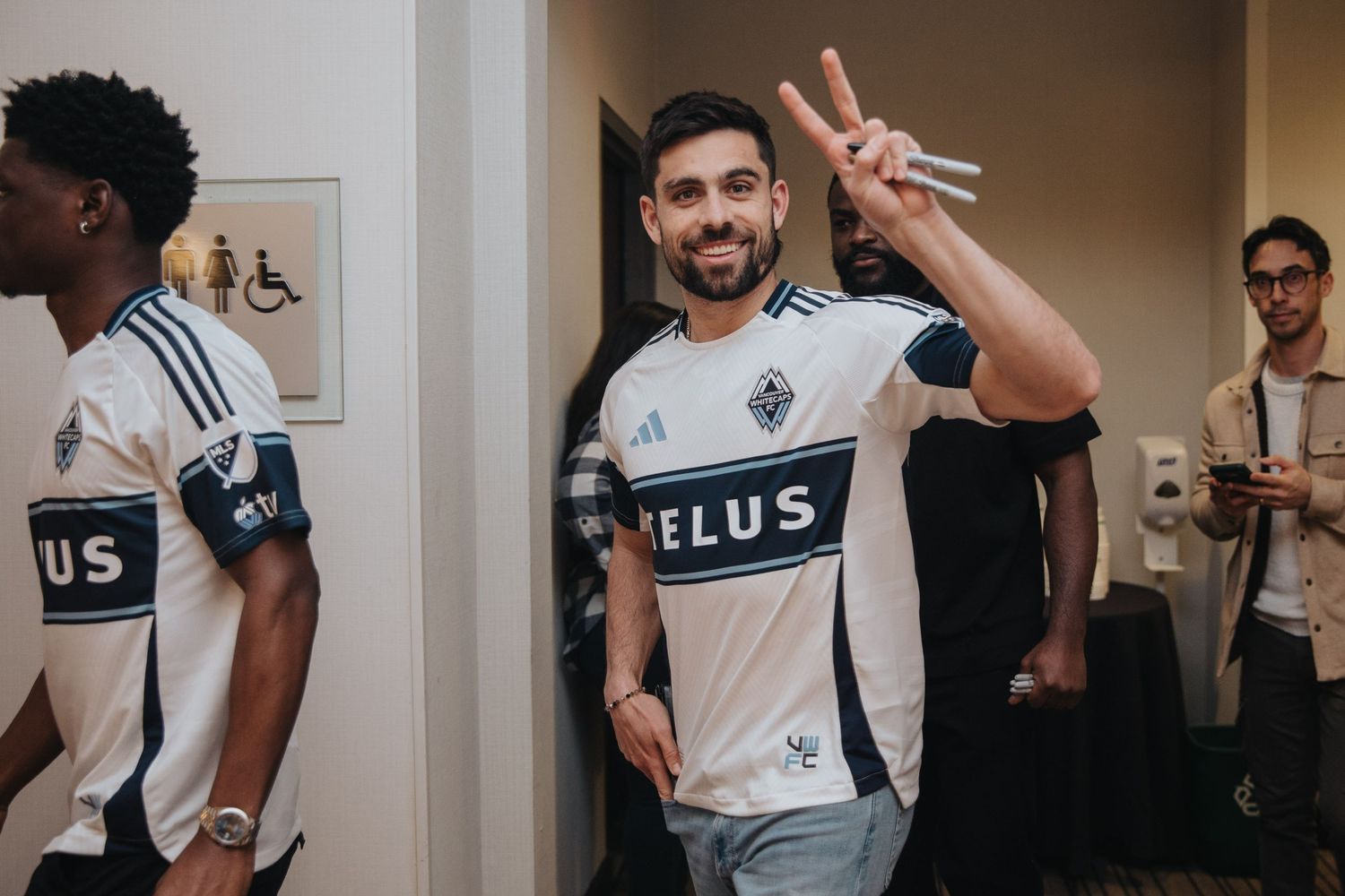 Team members in white jerseys sharing casual moments backstage at a gaming event.
