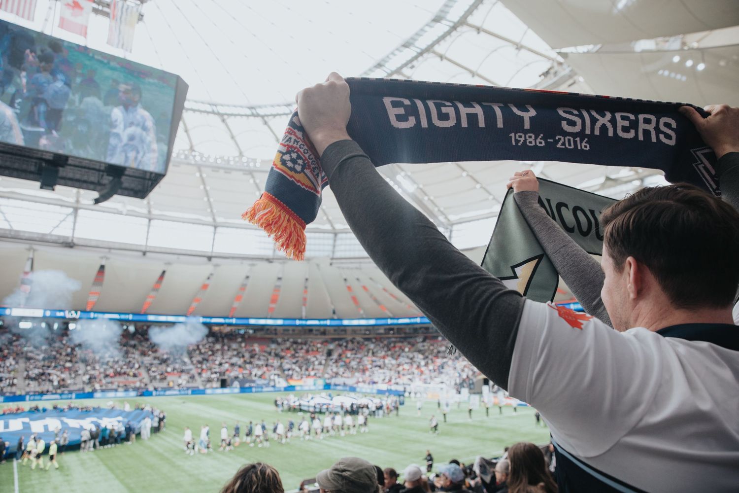 Soccer fan holding up team scarf inside BC Place stadium during match.