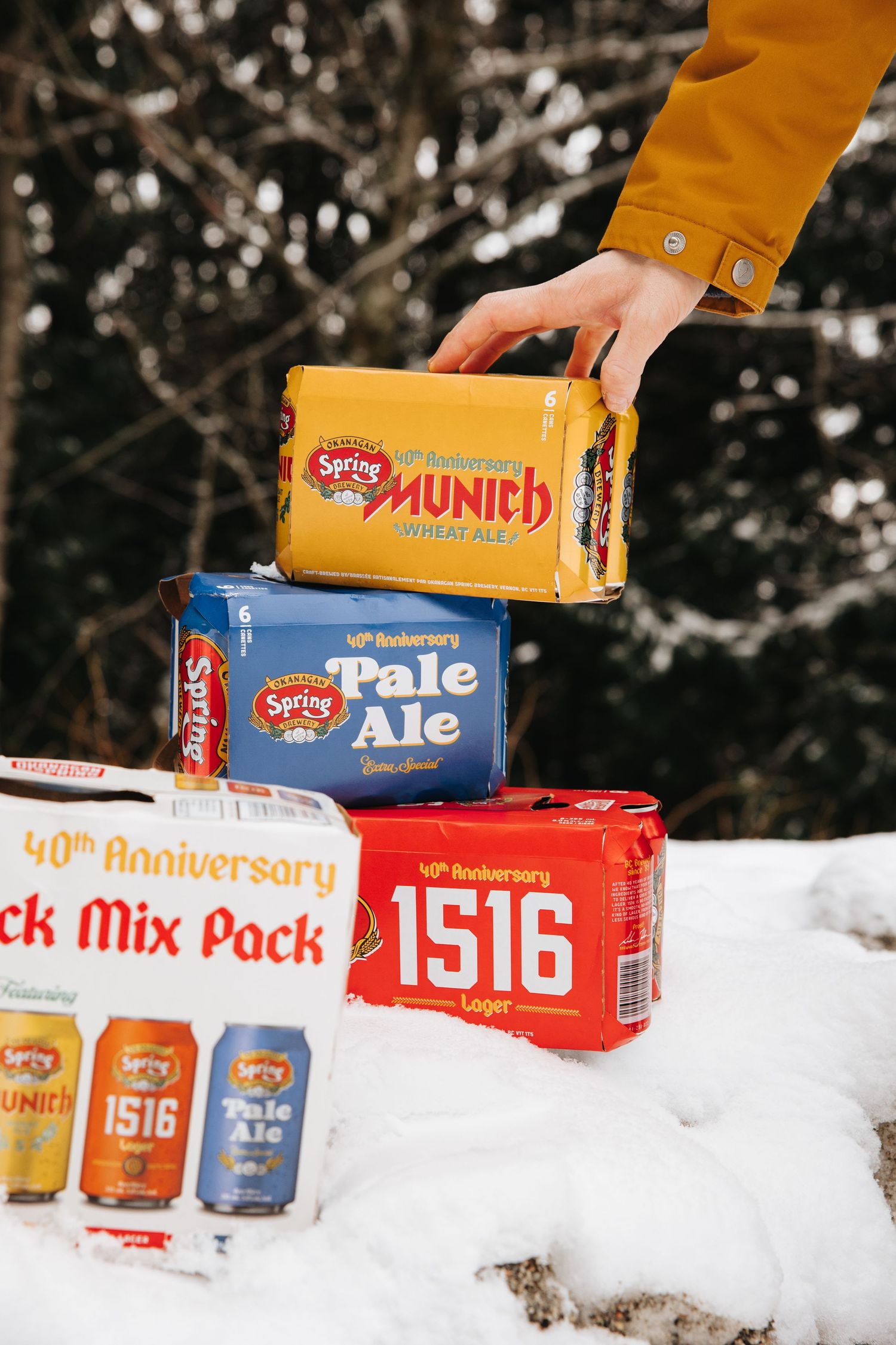 Spring Brewery beer cases and cans arranged in snow with 1516 and Pale Ale varieties visible.