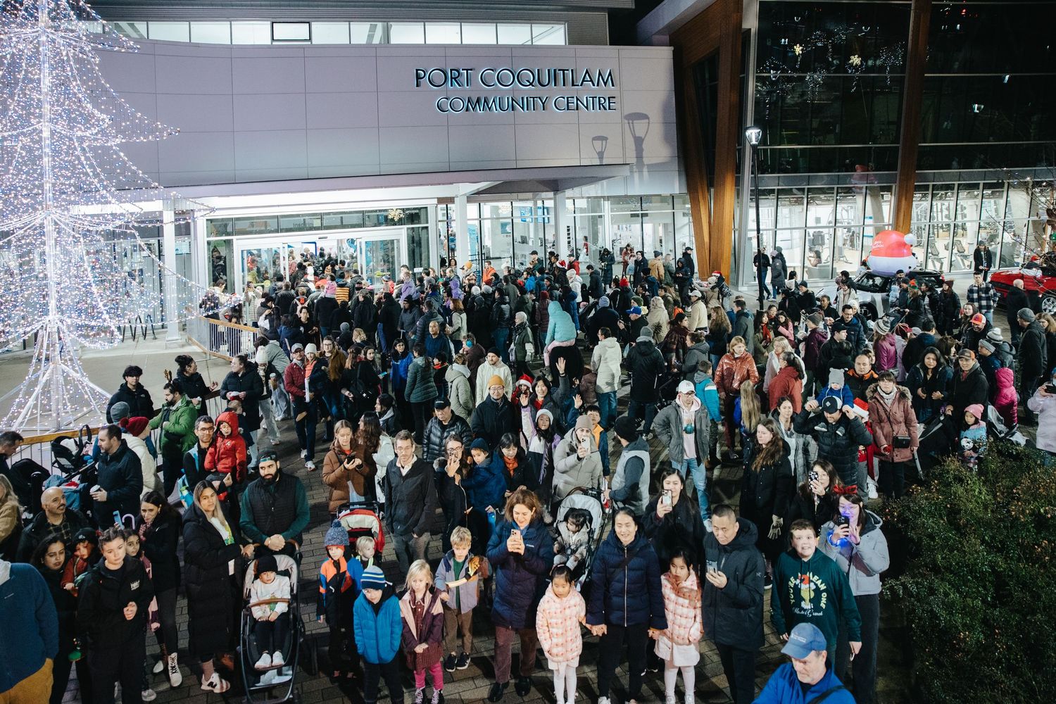 Panoramic view of crowded indoor event space with winter decorations.