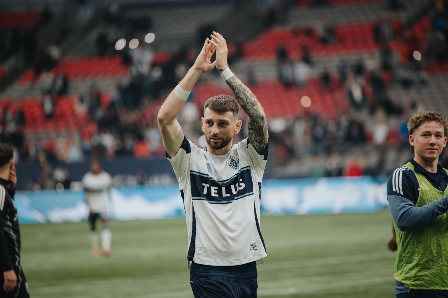 Soccer players celebrate on the field with raised arms and joyful expressions.