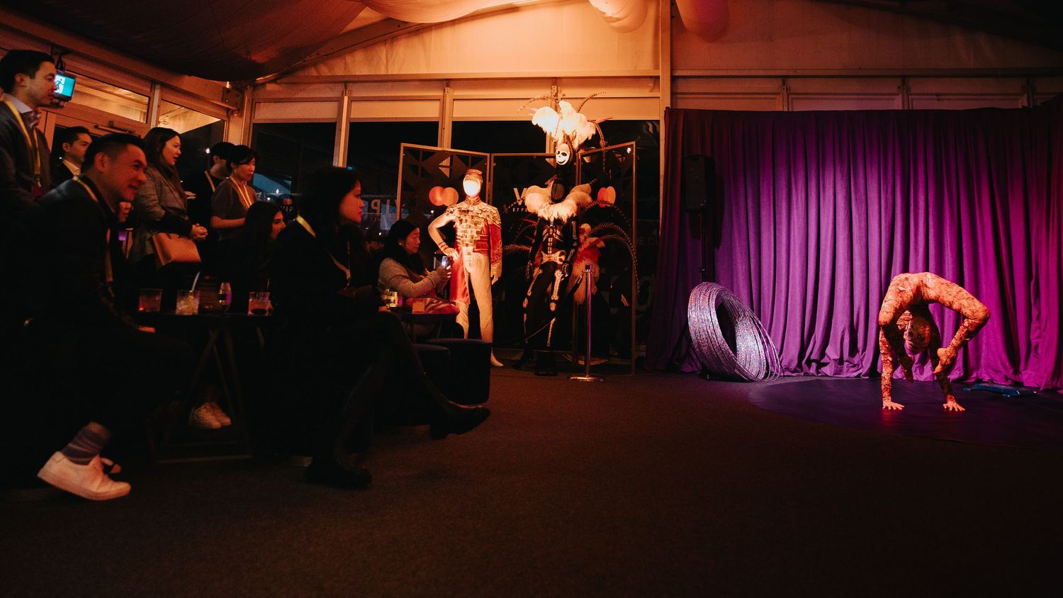 Dark restaurant interior illuminated by moody red lighting and purple curtains.