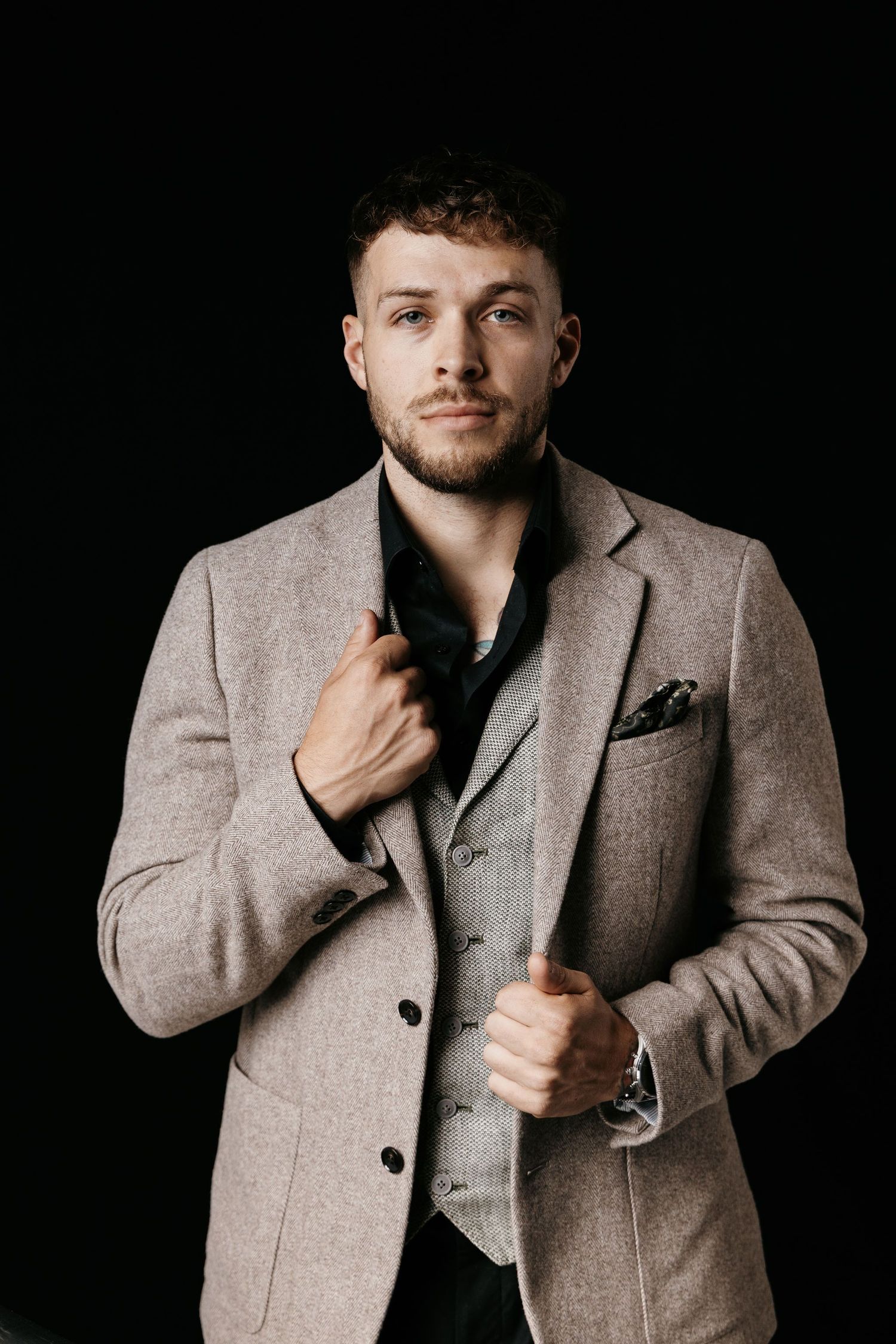 Professional studio portrait series showing a person wearing a gray wool blazer and vest against a dark background.
