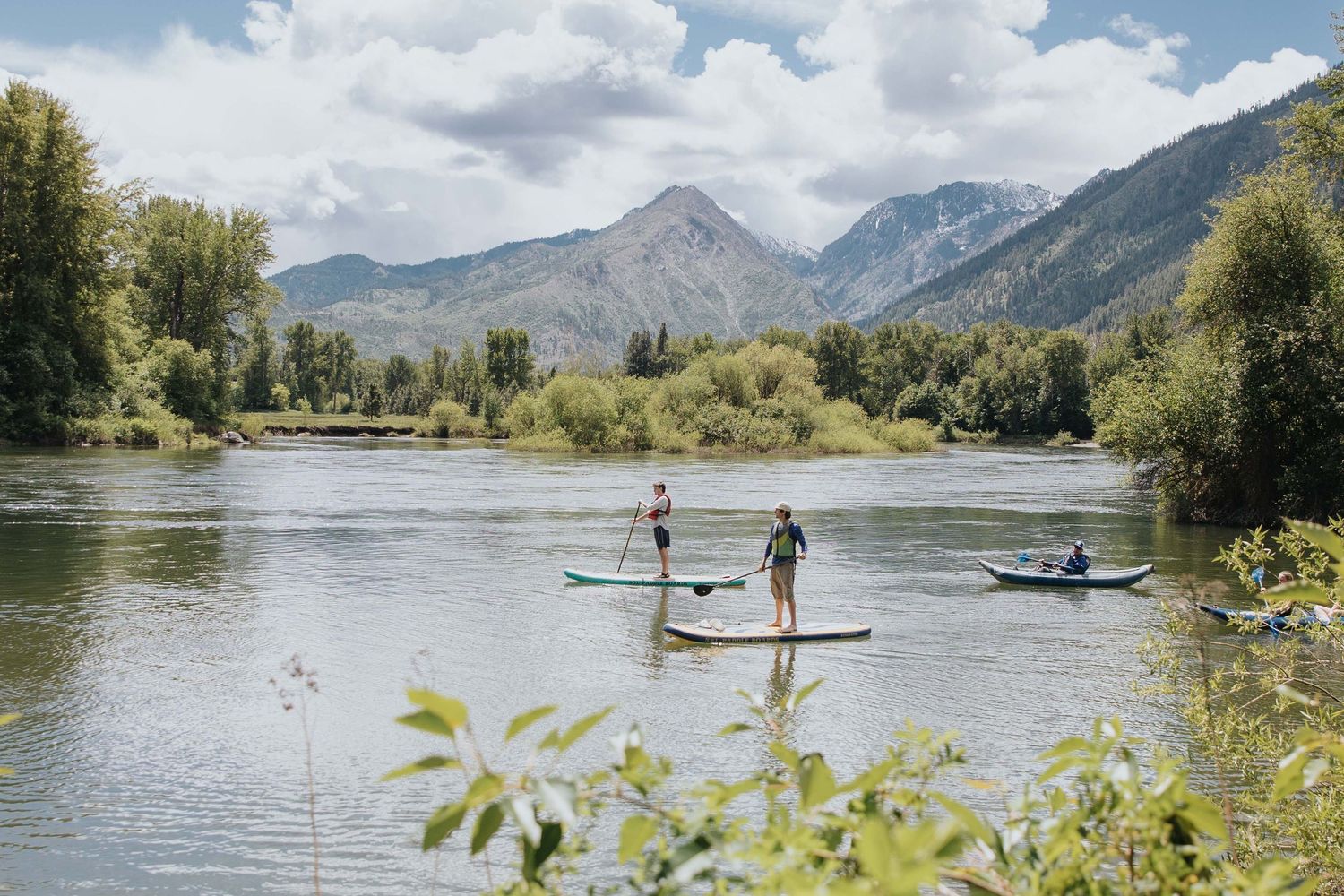 Scenic mountain lake with paddleboarders enjoying water activities on a sunny day.