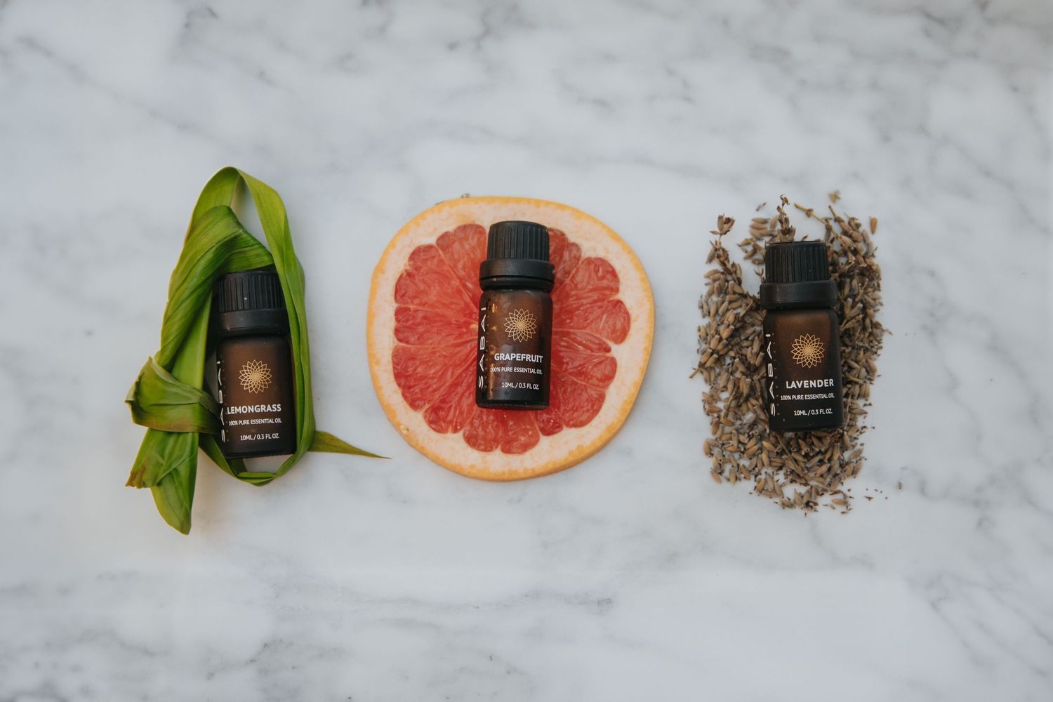 Minimalist product photography of small electronics arranged with citrus and leaves on marble surface.