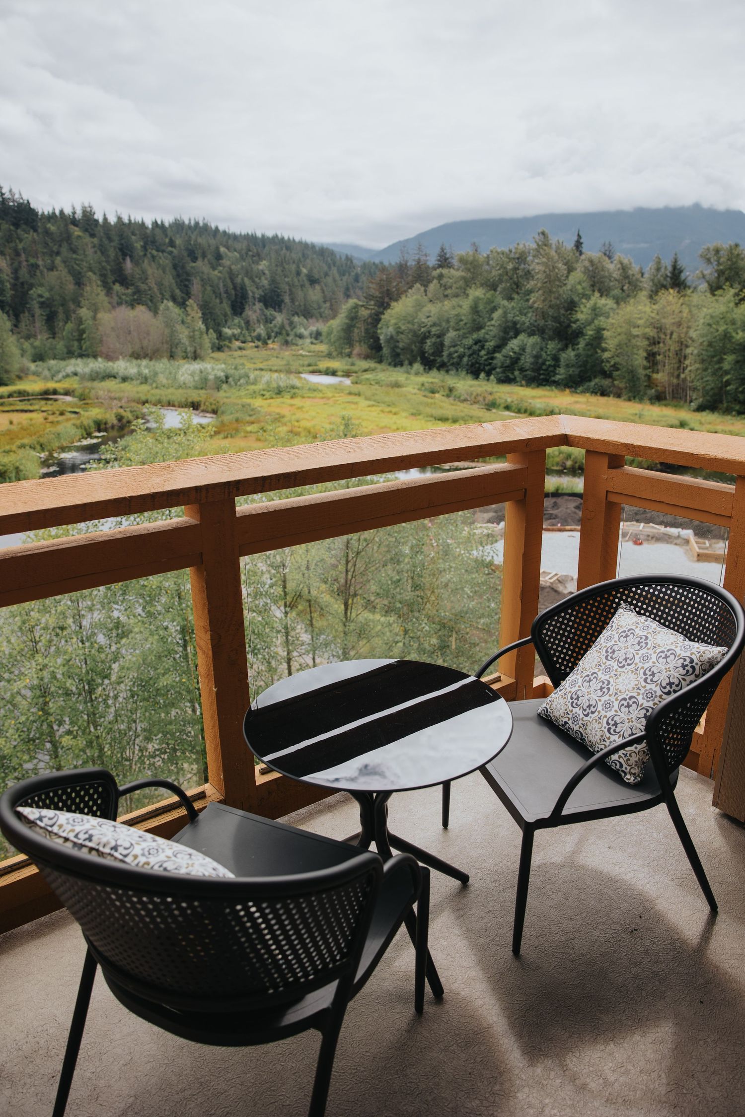 Outdoor terrace with modern black furniture offering panoramic views of mountain valley.