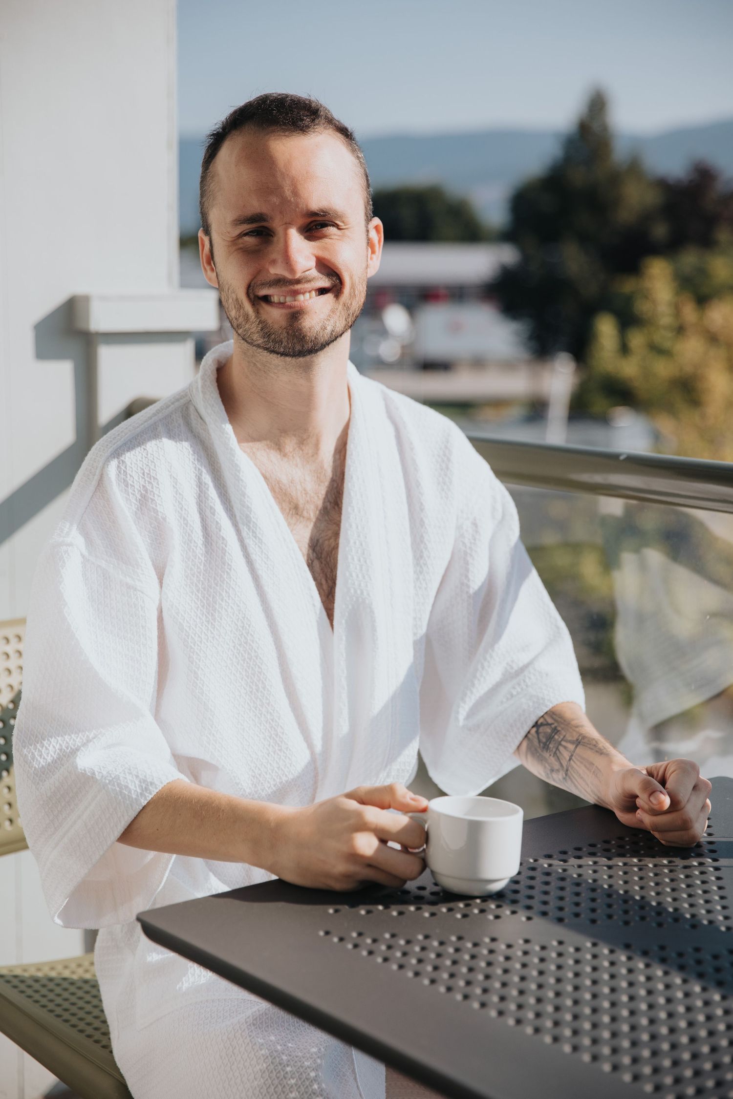 Person in white bathrobe relaxing on outdoor patio furniture.