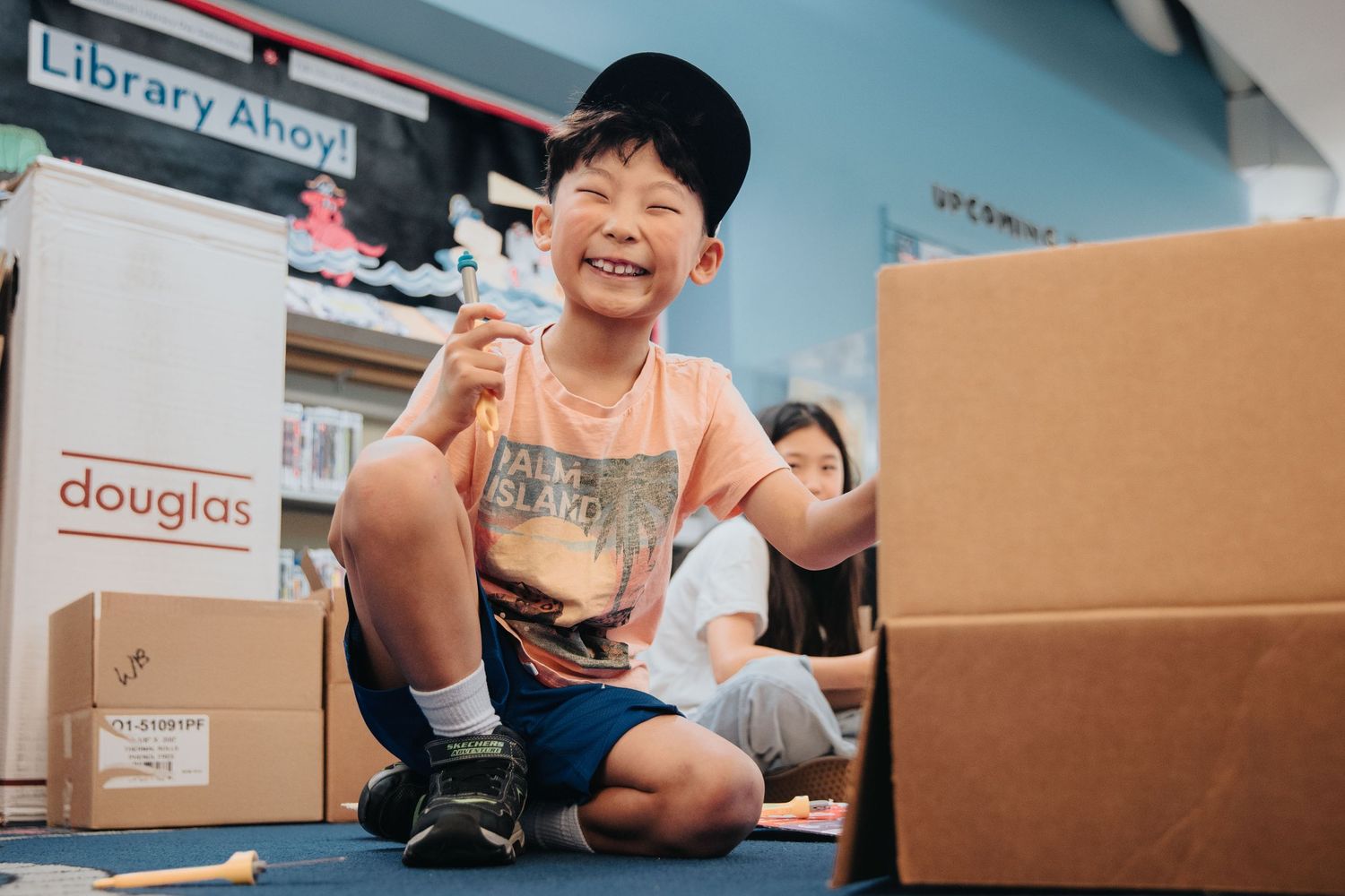 Kids exploring cardboard boxes in a library setting.