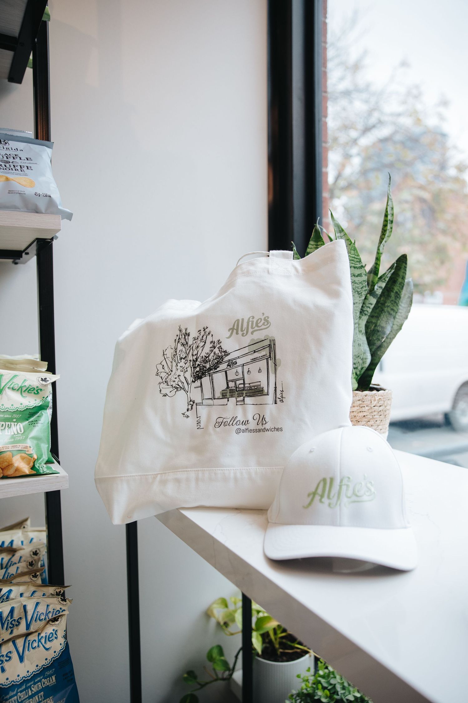 White branded shopping bags displayed on shelves with green plant accents.