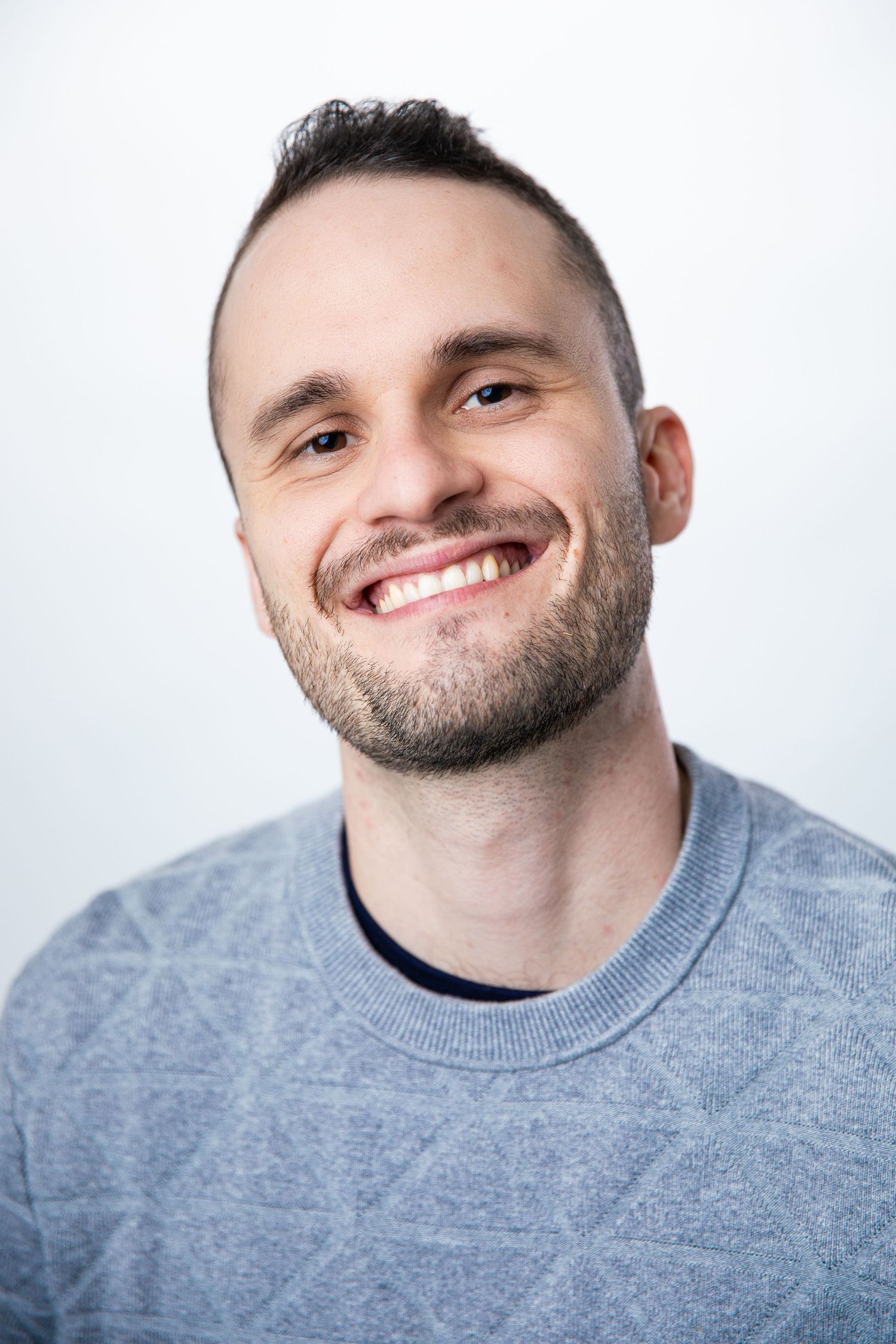 Casual headshot portraits of person in grey sweater against white background.