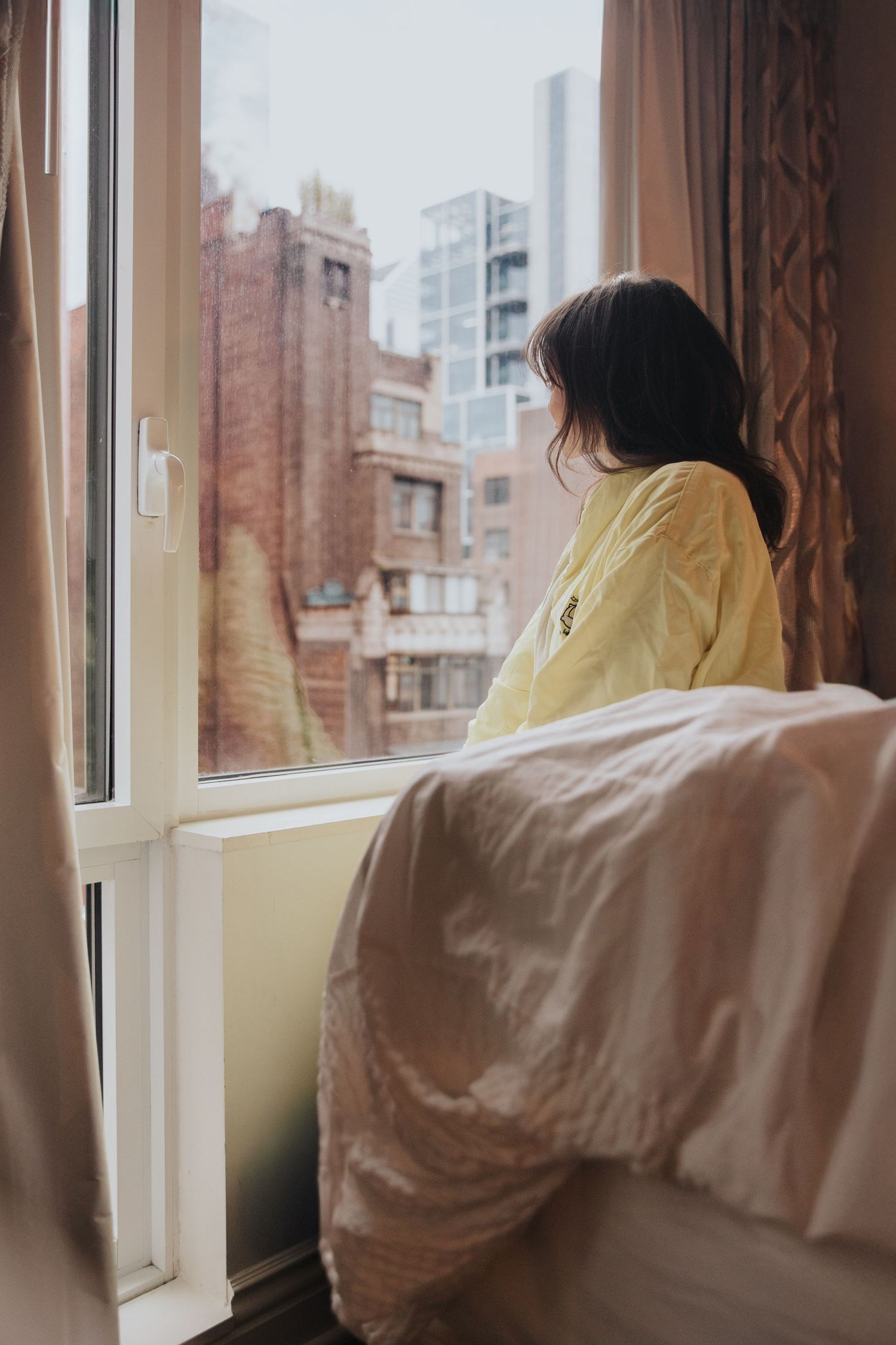 Soft morning light streams through a window with white curtains in a cozy bedroom setting.