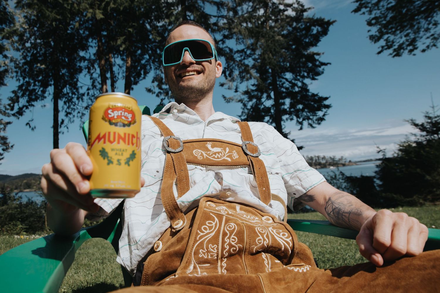 Person holding a canned beverage against a scenic outdoor backdrop with trees.