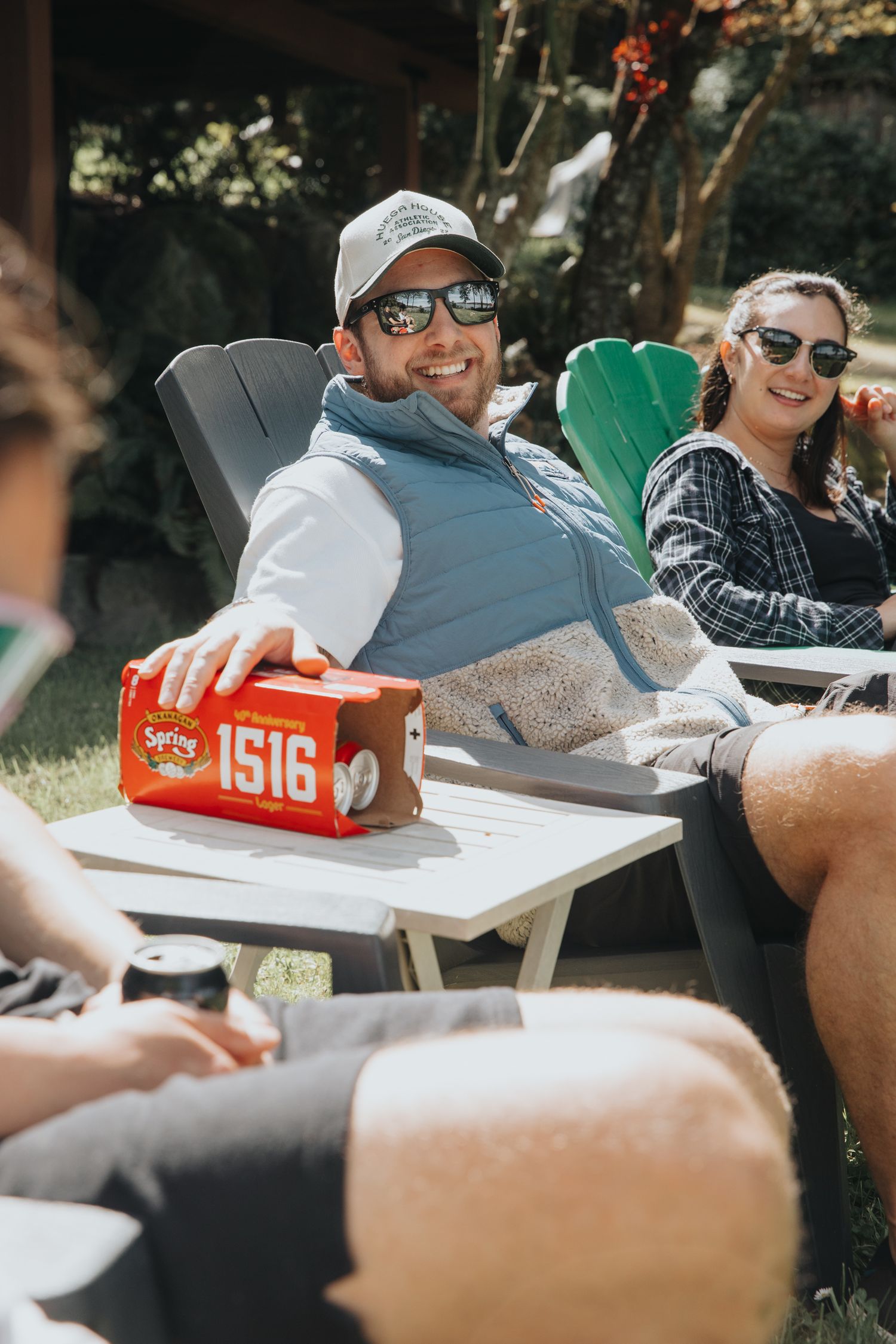 Group hanging out at a picnic table with beverages and casual conversation.