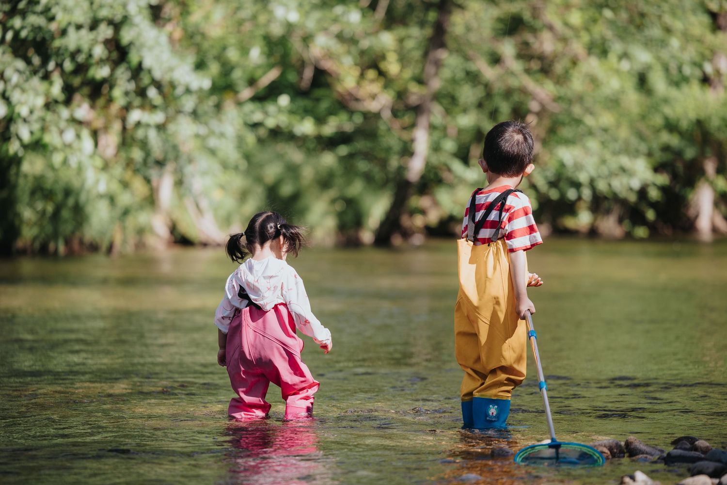 Children splashing and playing in shallow river water during summer.