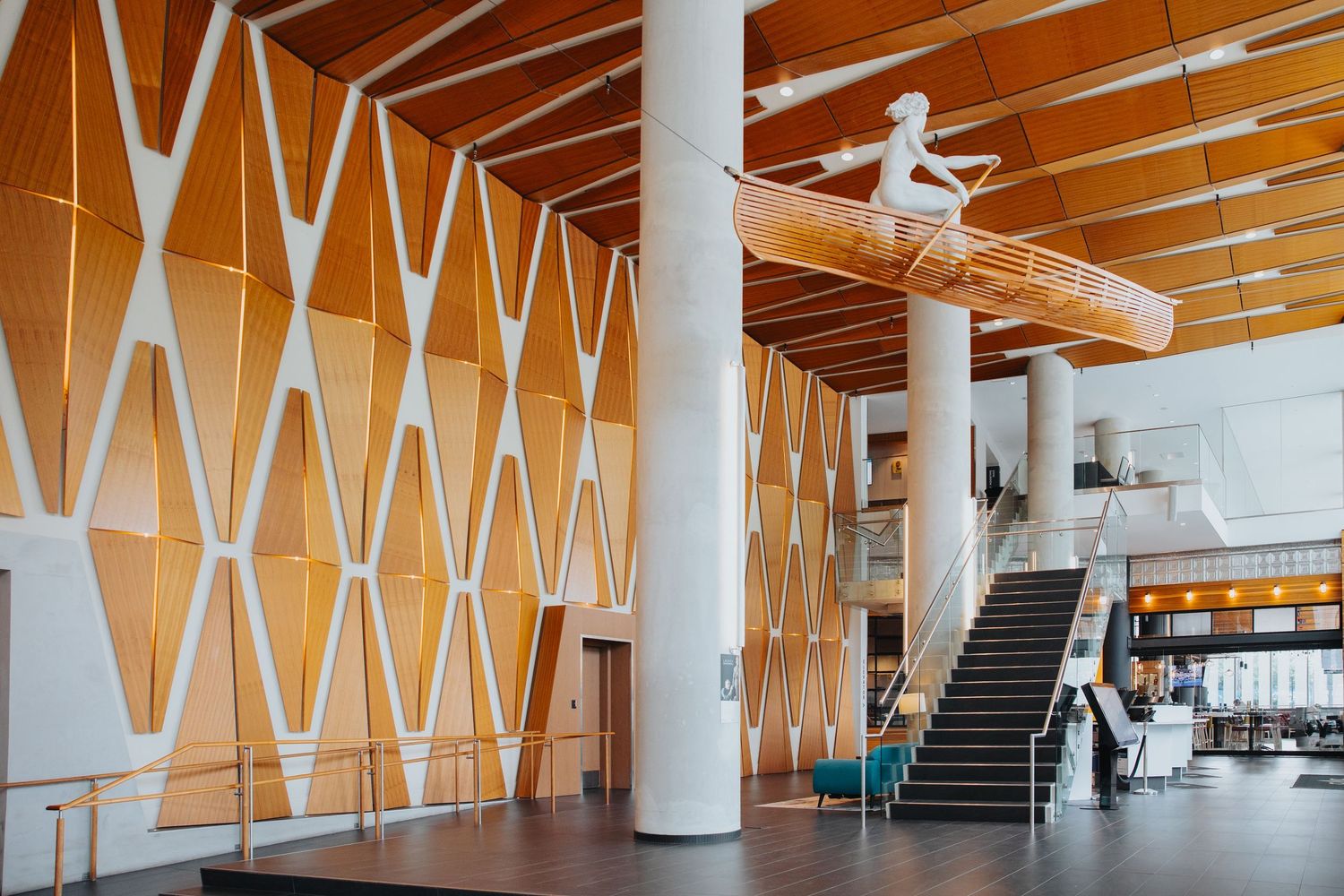 Modern lobby interior with geometric wood paneling and white columns.