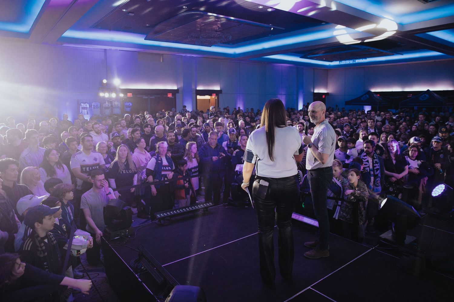 Large conference hall with blue lighting and packed audience.