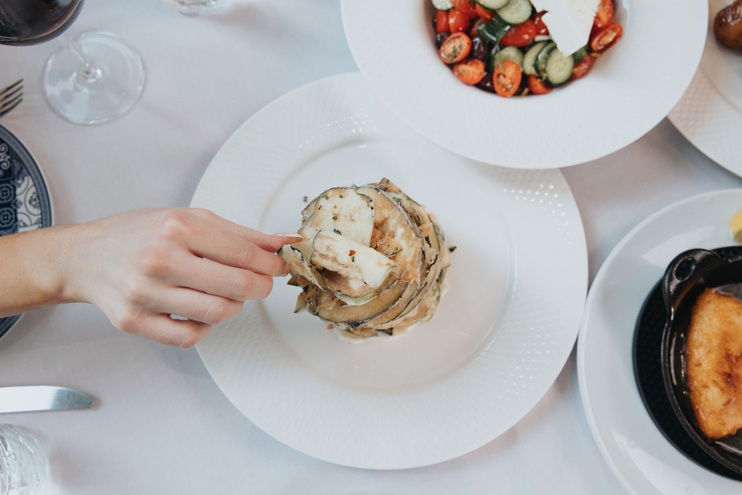 White plates with gourmet food dishes arranged on a dining table.