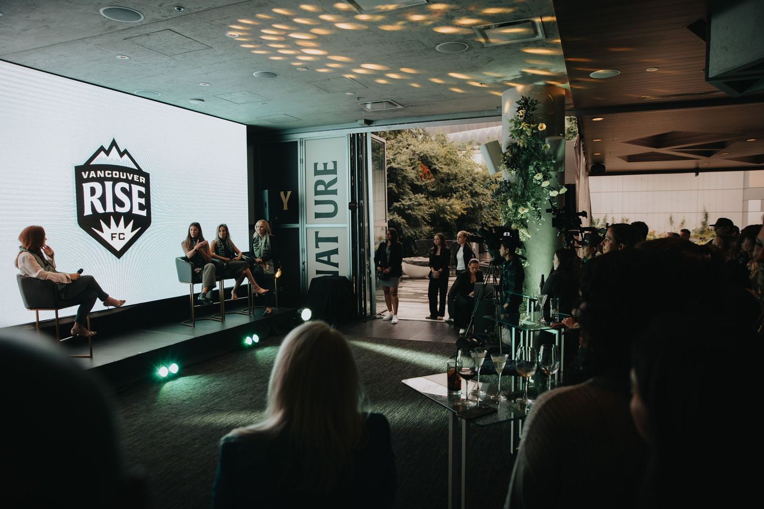 Dark conference room with RISE logo projected on screen during presentation.