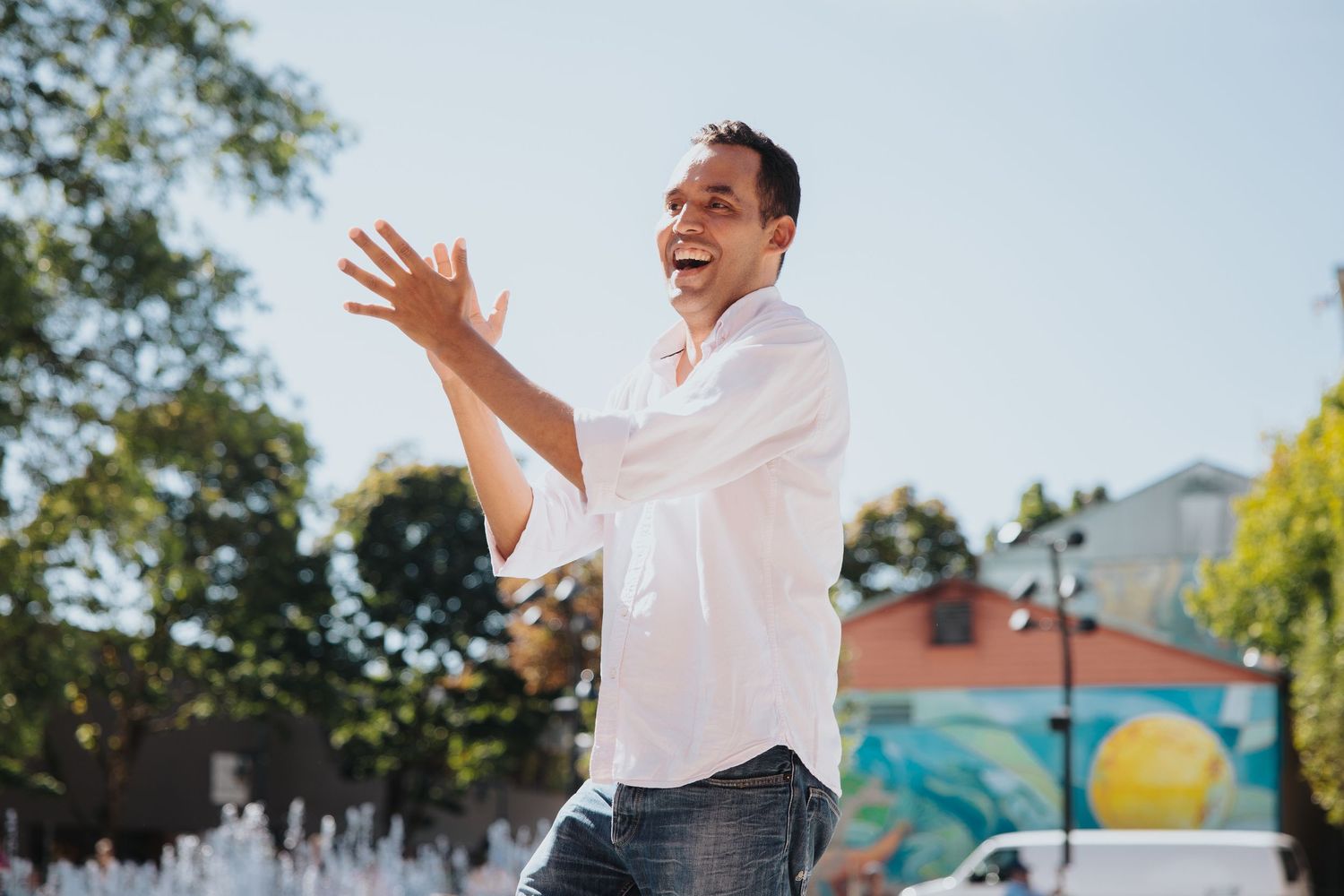 Performer in white shirt gesturing enthusiastically during outdoor show.