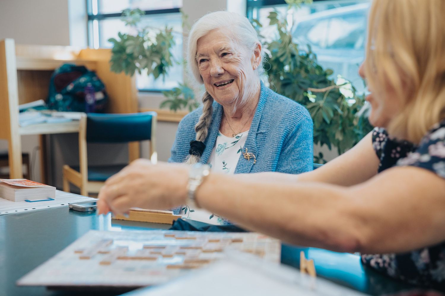 People sitting at tables engaged in group activities in a bright indoor space.