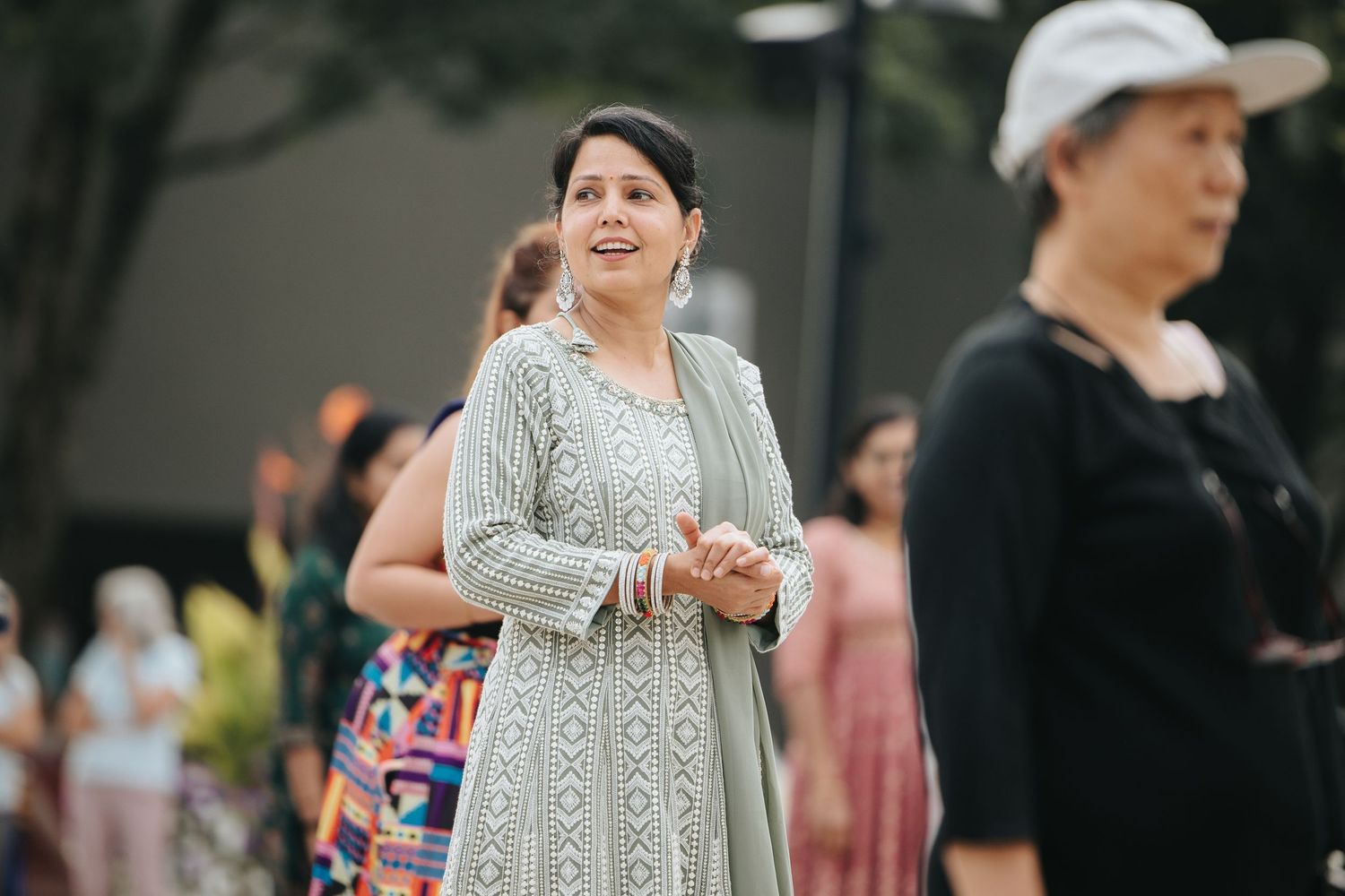 People enjoying an outdoor festival with pink and white decorations and string lights.