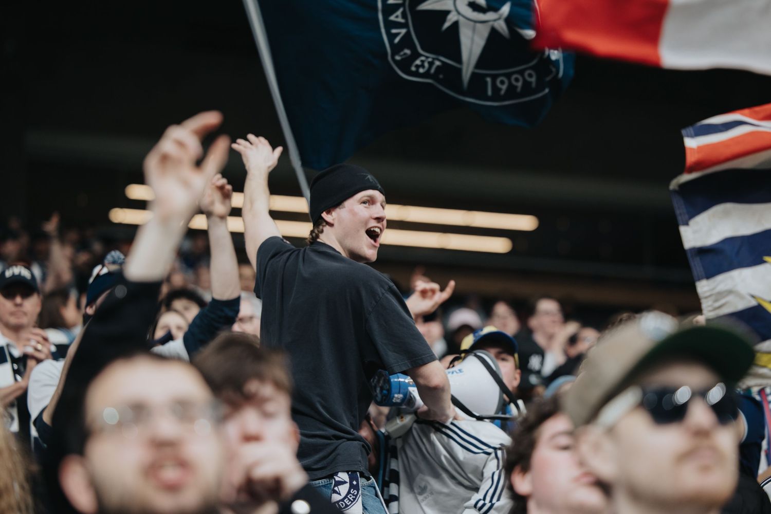 Enthusiastic sports fans react with excitement while watching a game from the stadium seats.