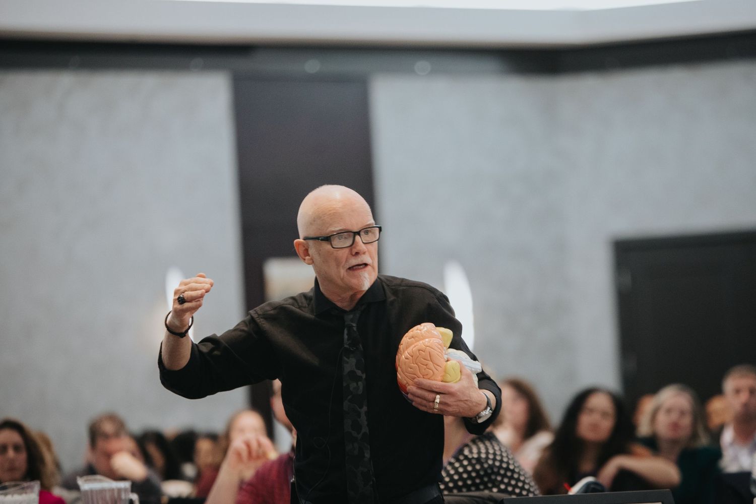 Speaker gesturing energetically during a presentation in a modern conference room.