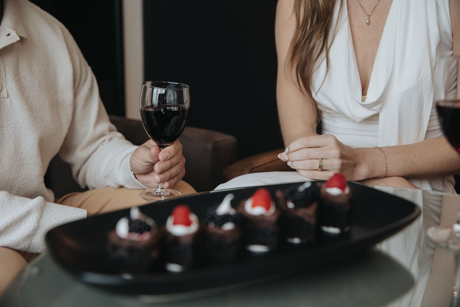Couple enjoying red wine with chocolate strawberry desserts at an elegant hotel restaurant.