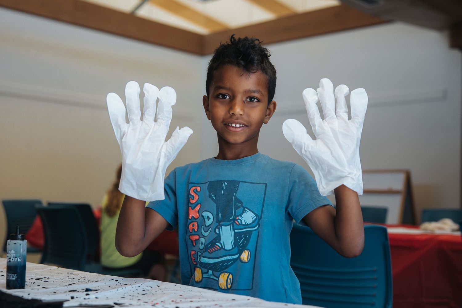 Youth wearing blue t-shirt showing white gloved hands during an activity.